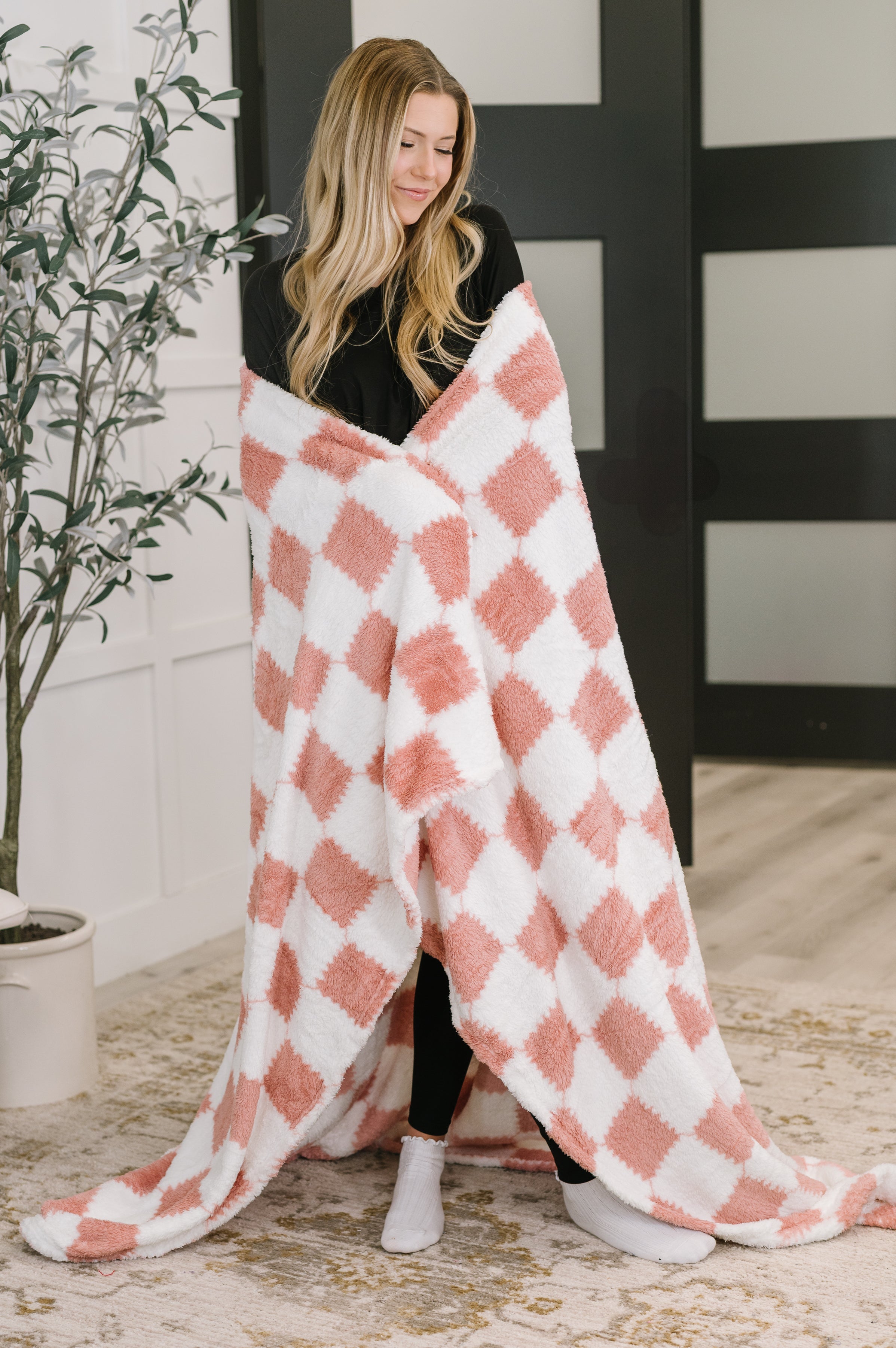 Woman wrapped in a pink and white checkered blanket in an indoor setting