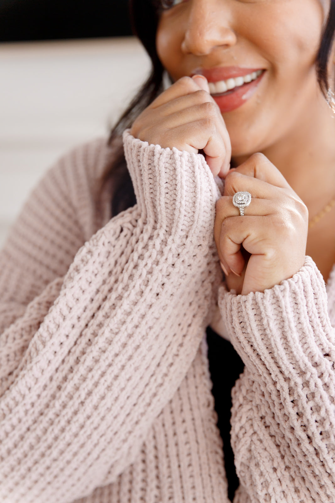 Woman wearing a light pink button down cardigan standing in an indoor setting.