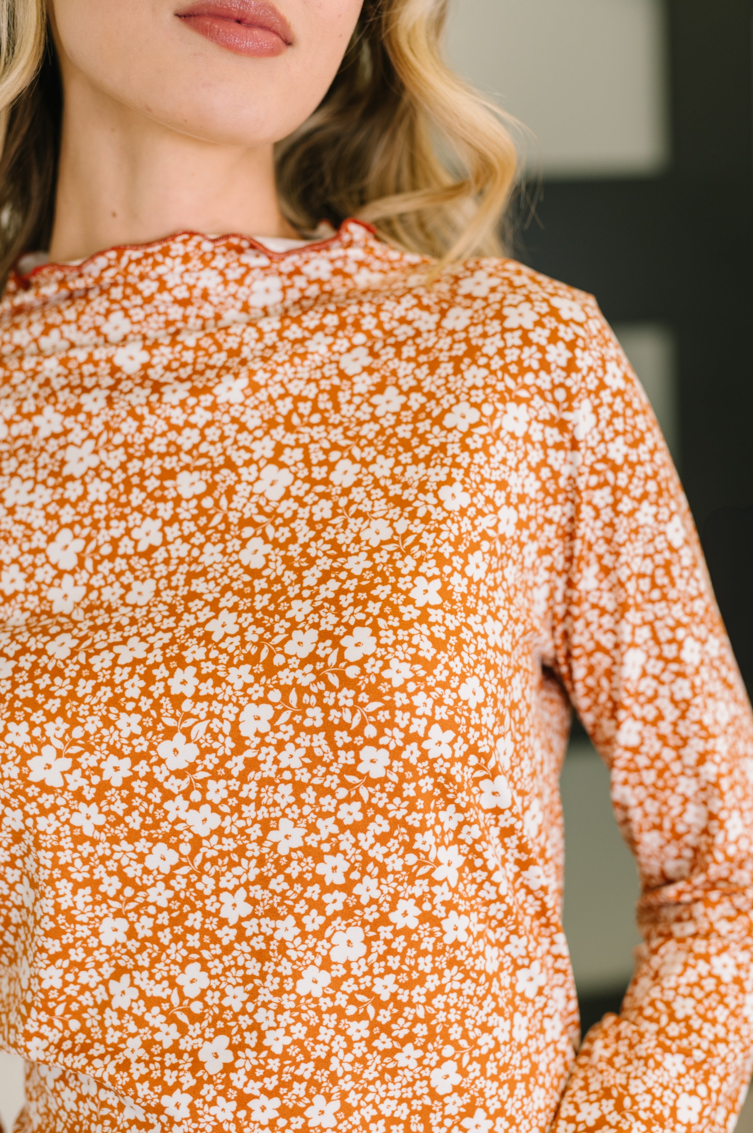 Close-up of a woman wearing a peach floral top with blurred background