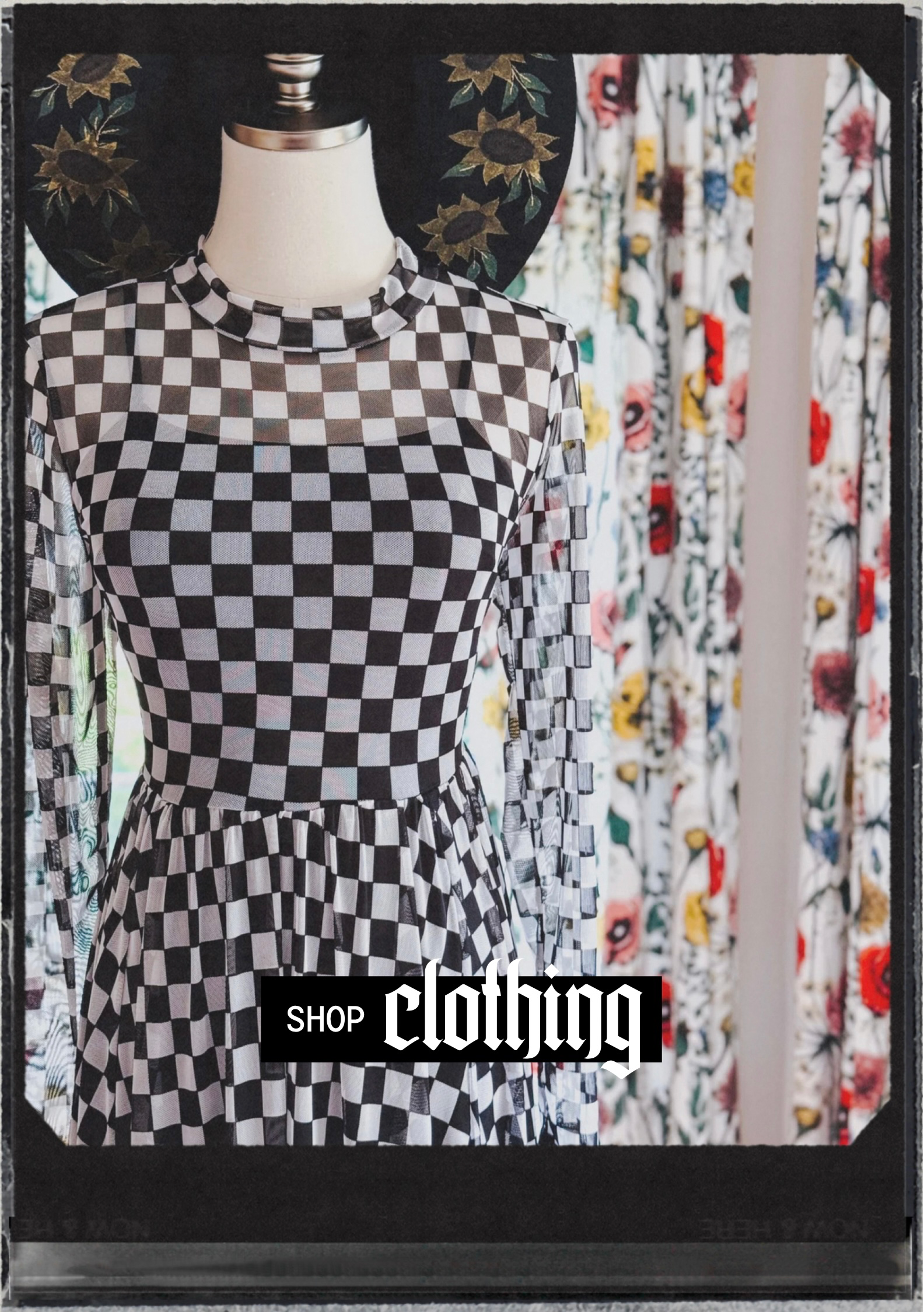 Checkerboard patterned long-sleeve dress displayed on mannequin with floral-patterned curtains in soft focus background