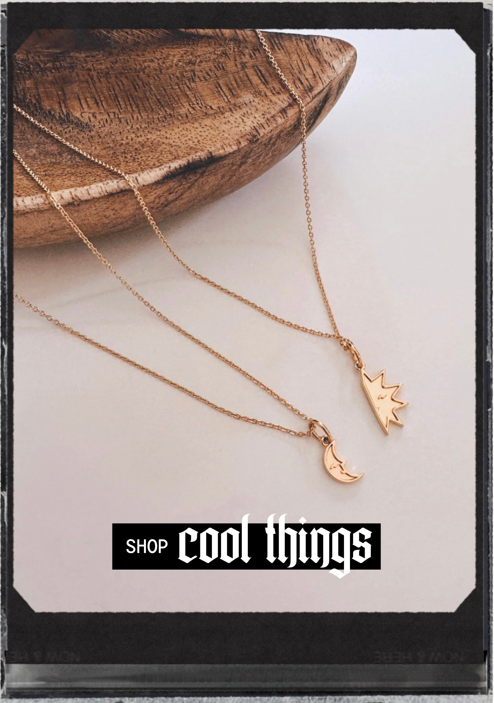 Two delicate gold necklaces with moon and crown charms displayed on a wooden bowl and light surface
