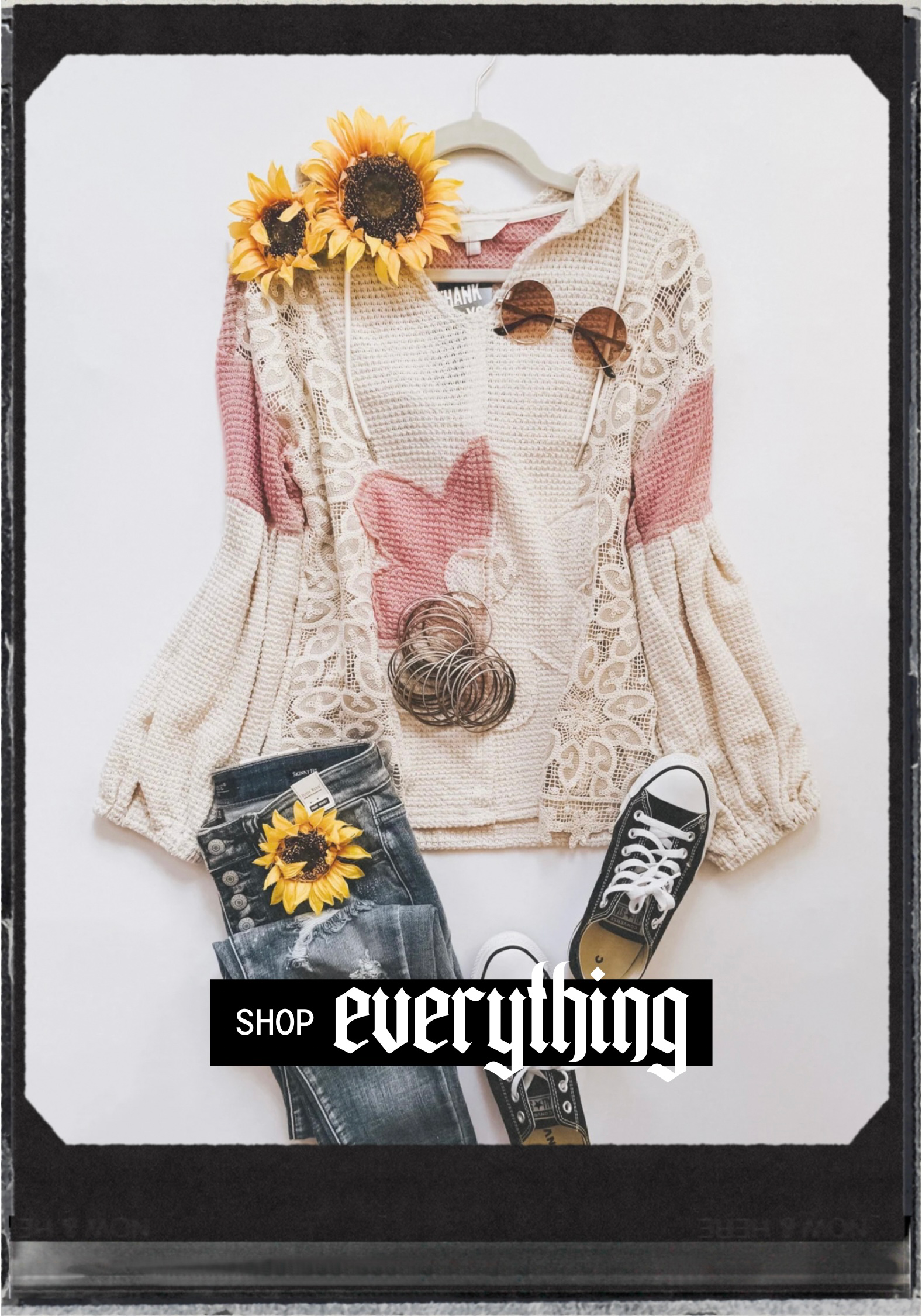 Soft knit sweater with floral accents paired with jeans, sneakers, sunglasses, and sunflower accessories on white background