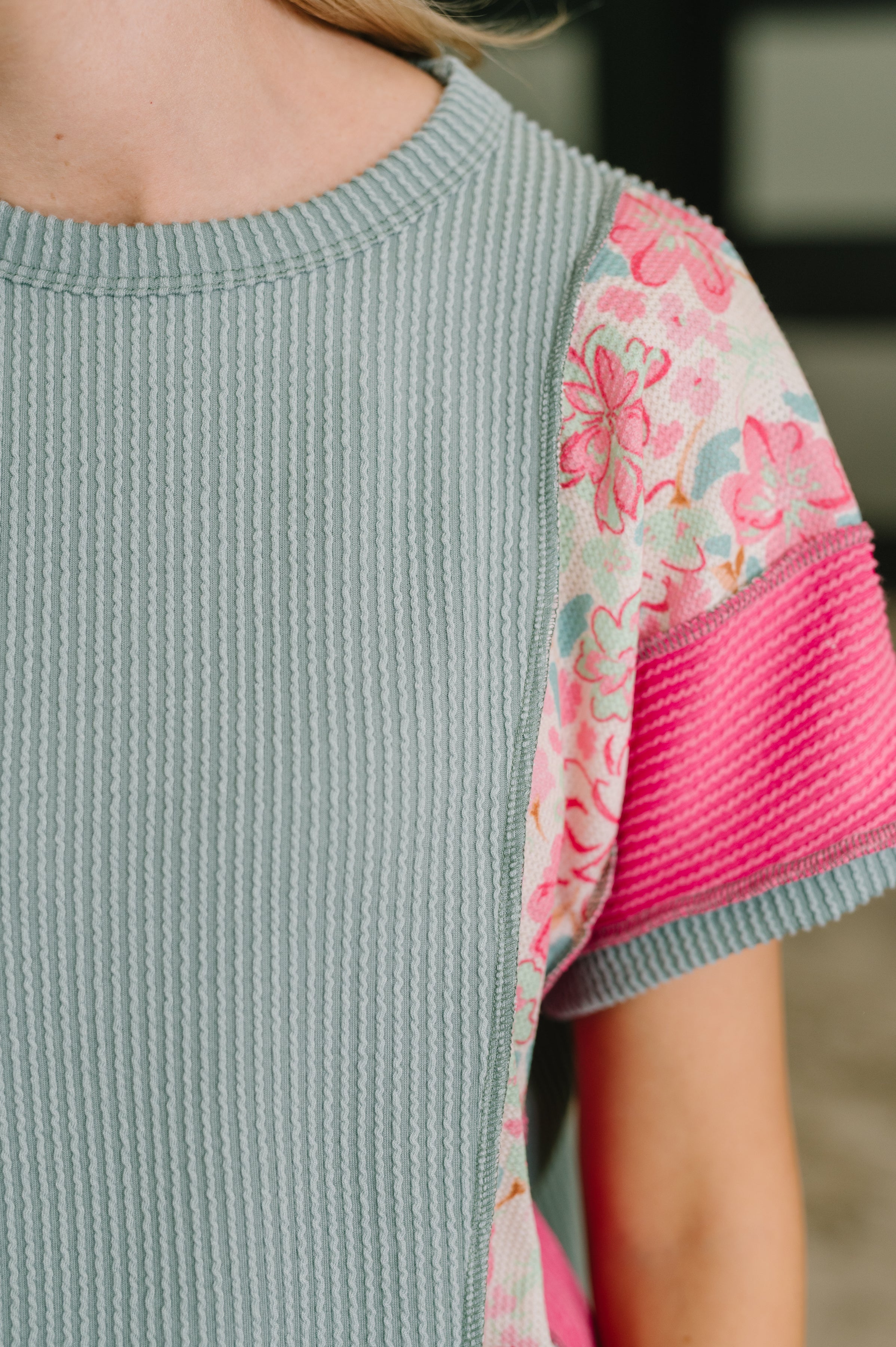 Close-up of textured knit top with blue cable ribbing and pink floral and striped color block sleeves.