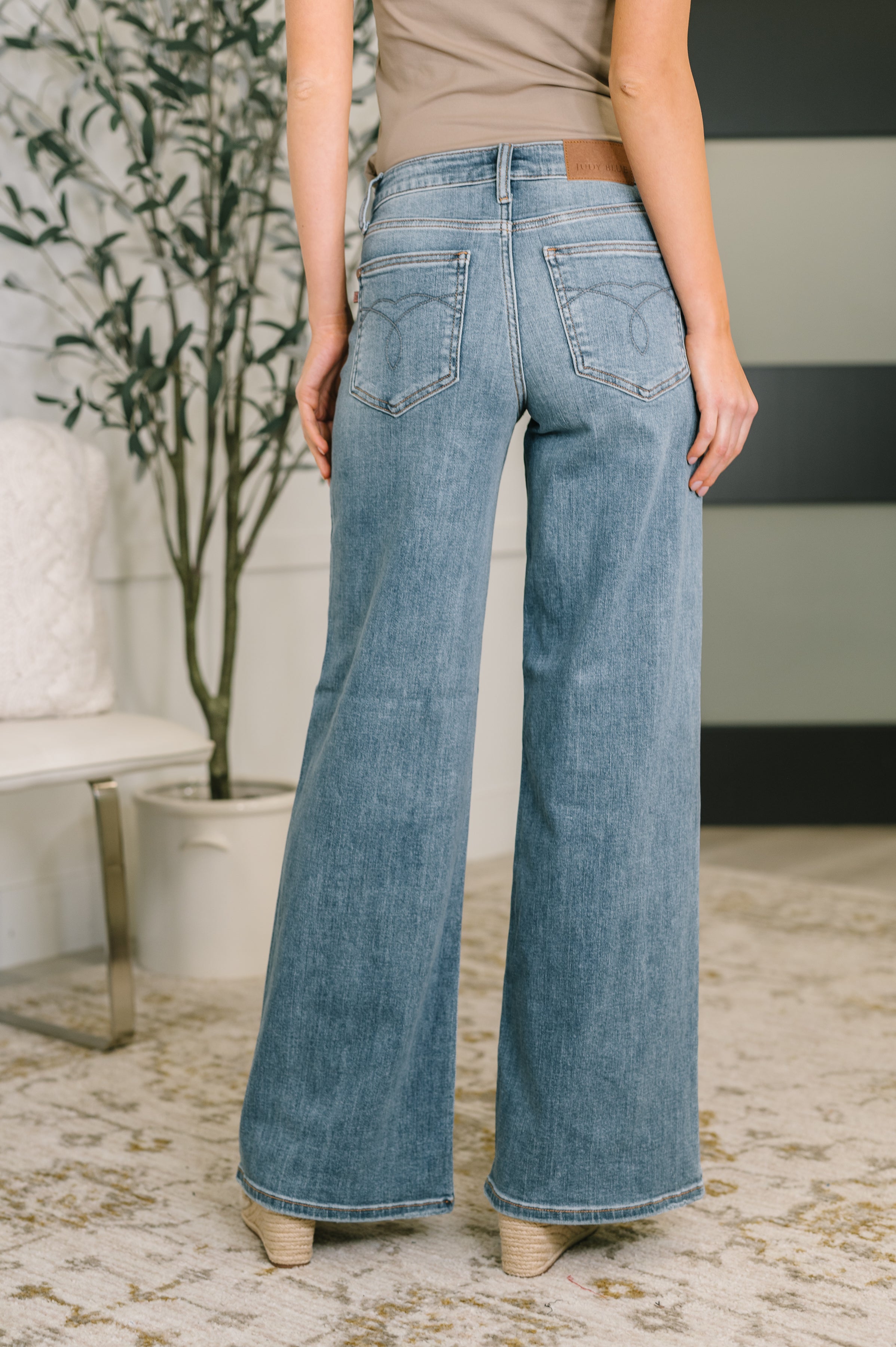 Back view of Adrian mid rise retro wide leg jeans in light wash denim worn indoors with beige shoes