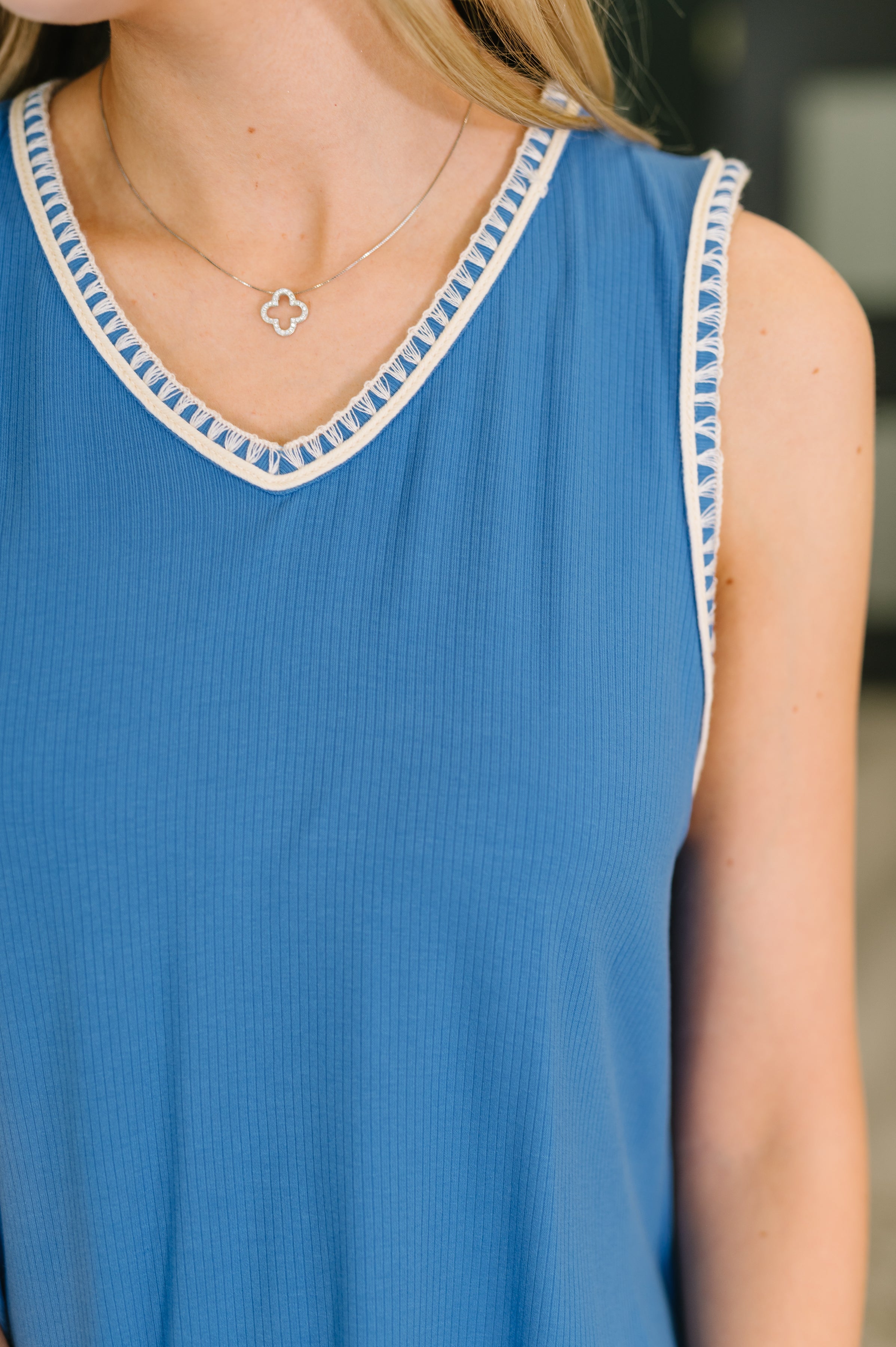 Close-up of ocean blue ribbed tank dress with cream trim detail along neckline and armholes worn with delicate silver necklace