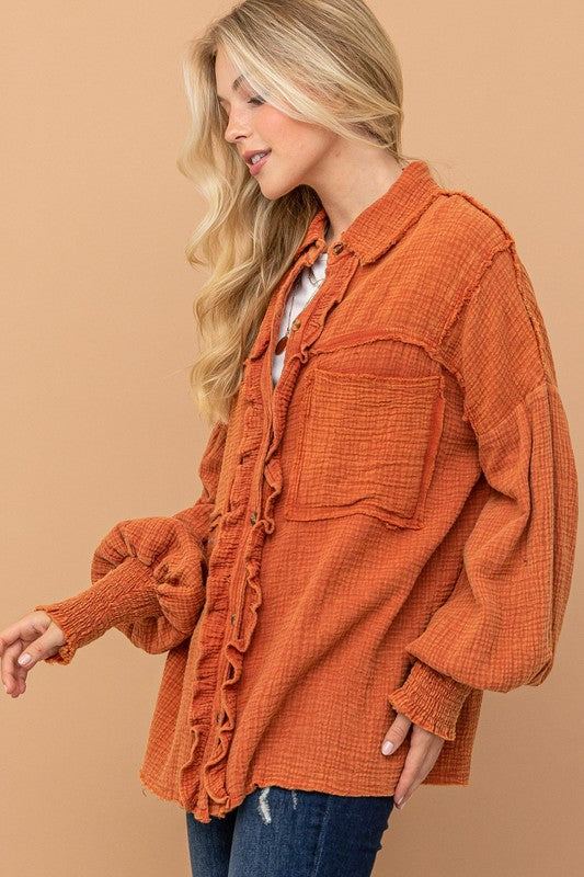 Blonde woman in textured burnt orange All Pan Out shirt with ruffled placket and smocked cuffs side view against beige background