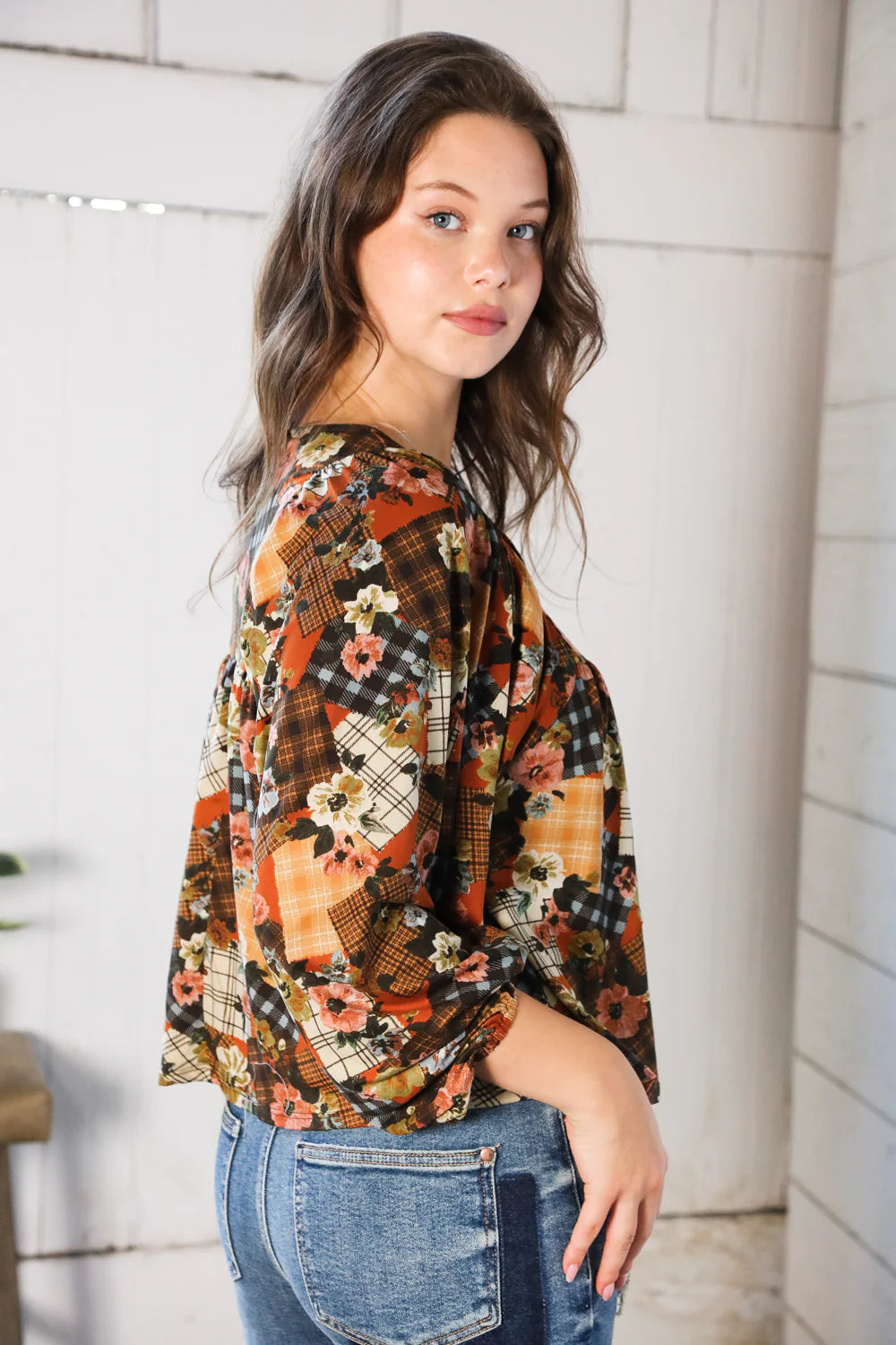 Woman wearing a floral patchwork print blouse with a neutral background