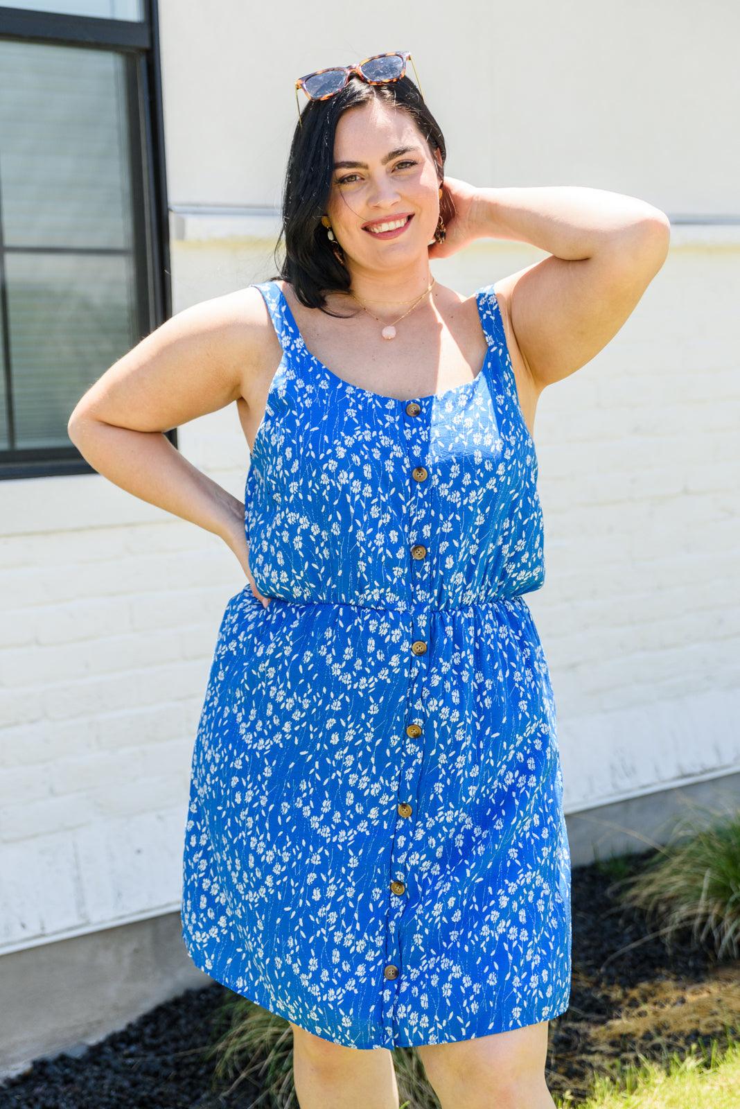 Woman wearing a blue floral dress standing outdoors.