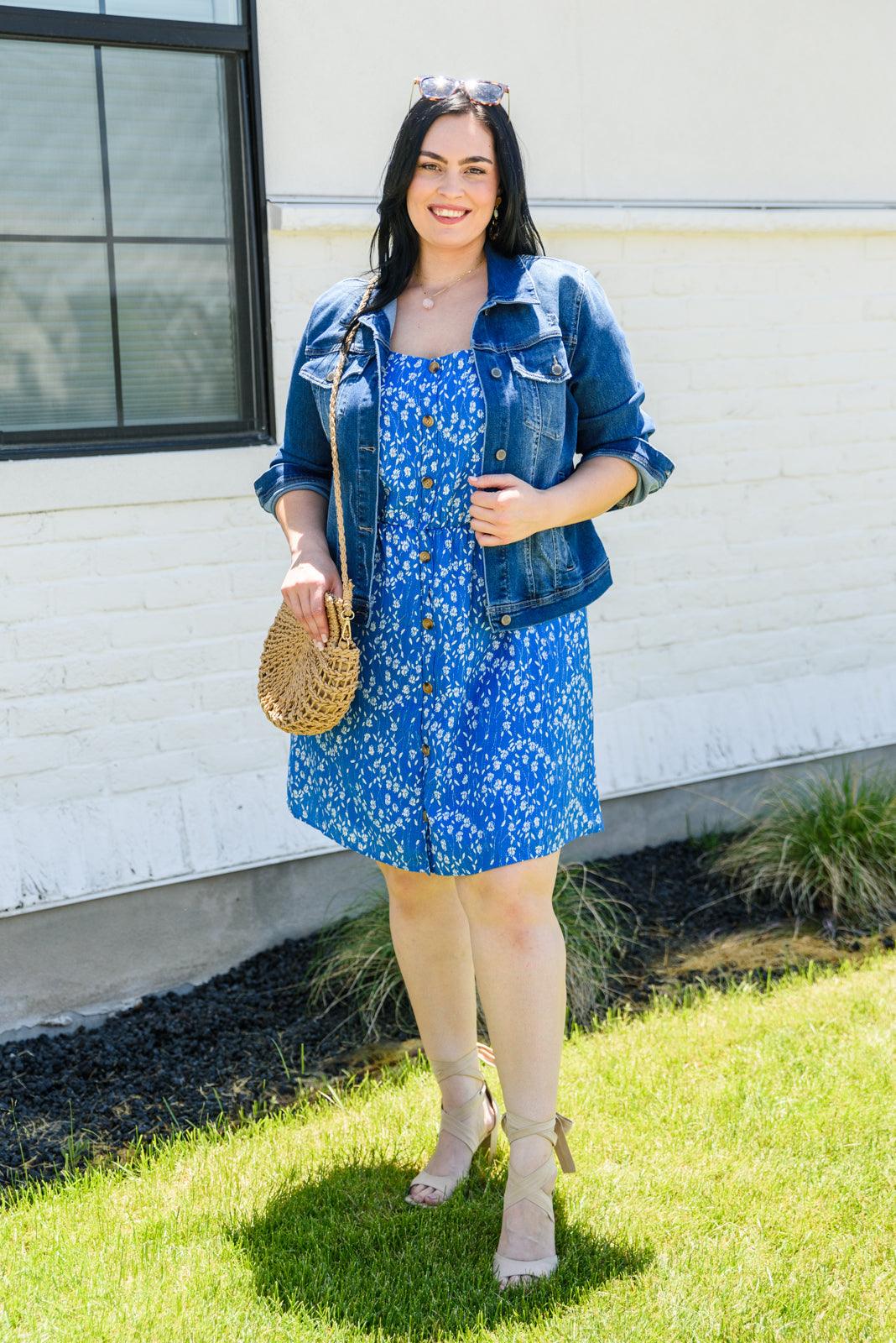 Woman wearing a blue floral dress standing outdoors.