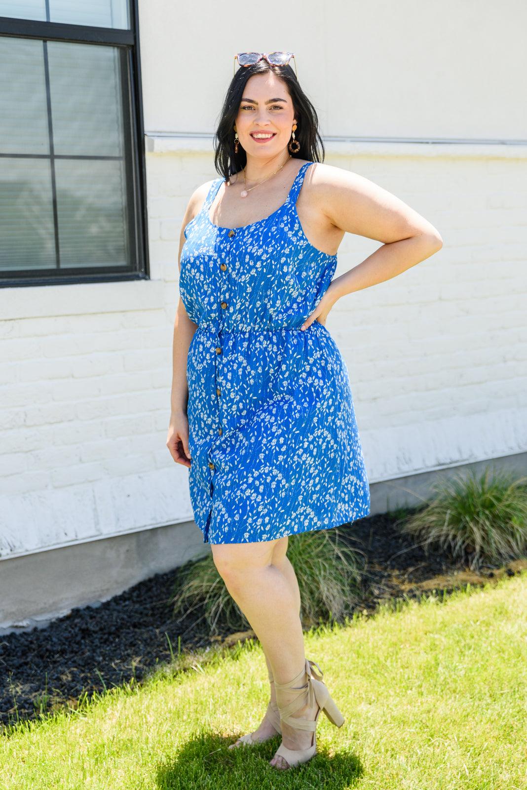 Woman wearing a blue floral dress standing outdoors.