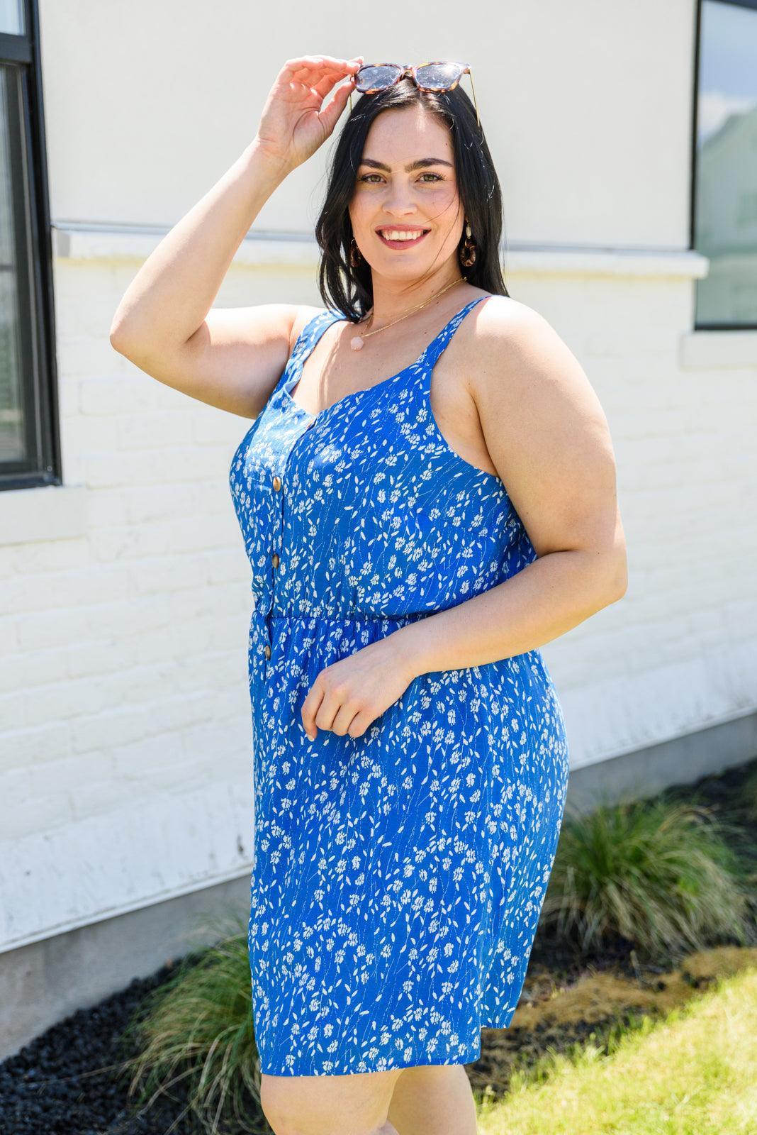 Woman wearing a blue floral dress standing outdoors.