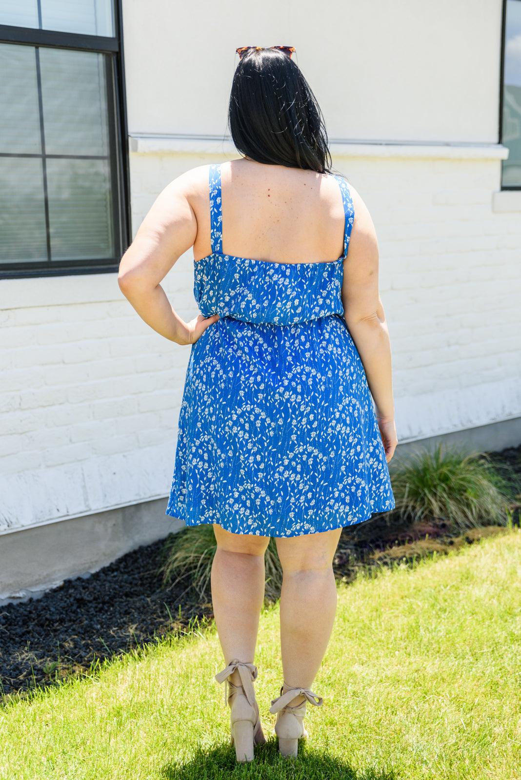 Woman wearing a blue floral dress standing outdoors.