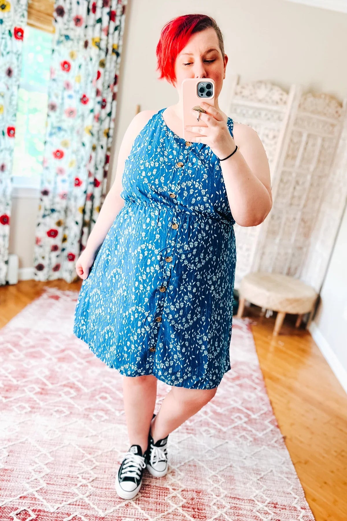 Woman wearing a blue floral dress standing indoors.