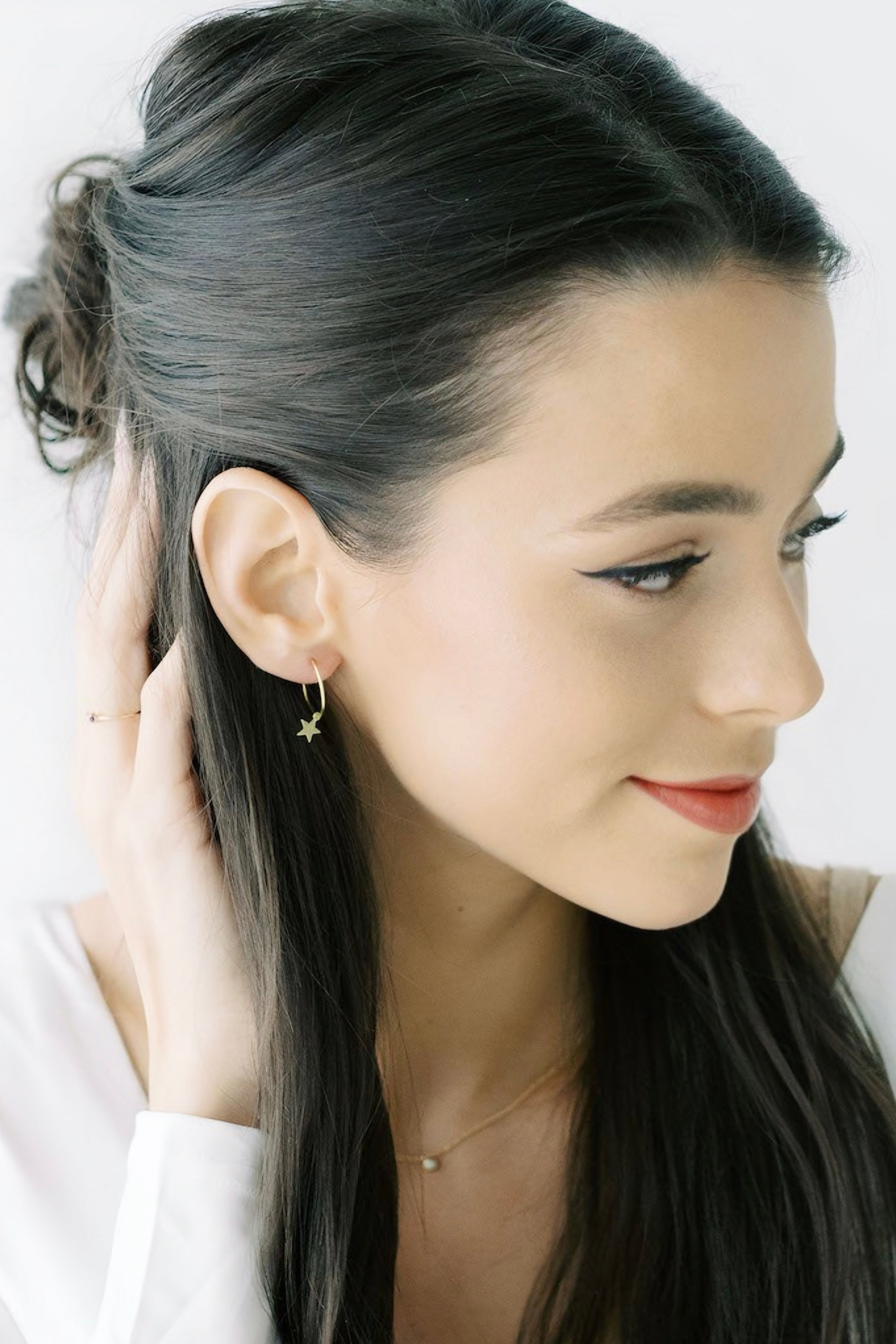 Woman with long dark hair wearing delicate gold star charm hoop earring AstraMagicCharmStarHoopEarrings4.jpg