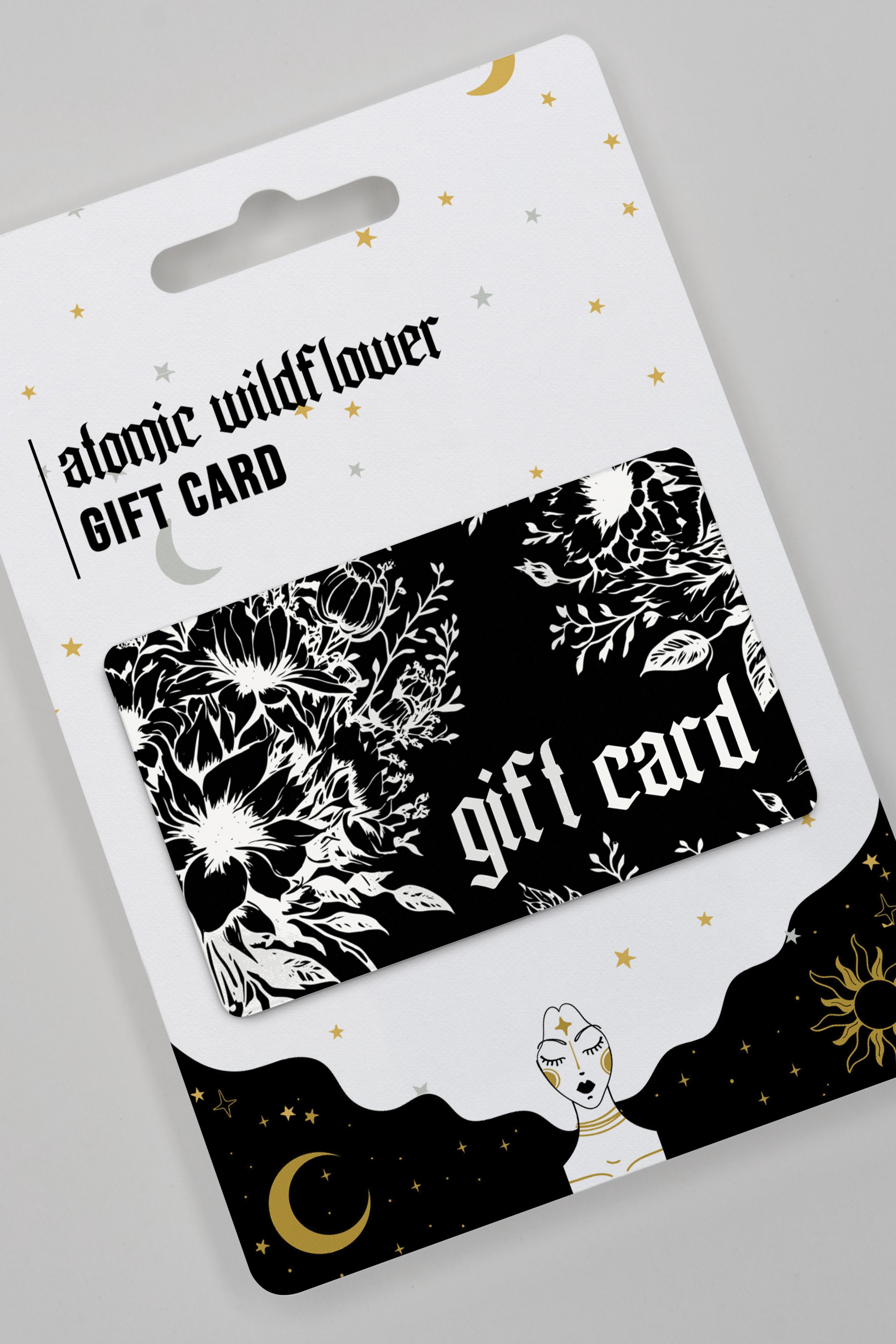 Atomic Wildflower gift card with white floral design on black, displayed on celestial-themed packaging, AtomicWildflowerEGiftCard