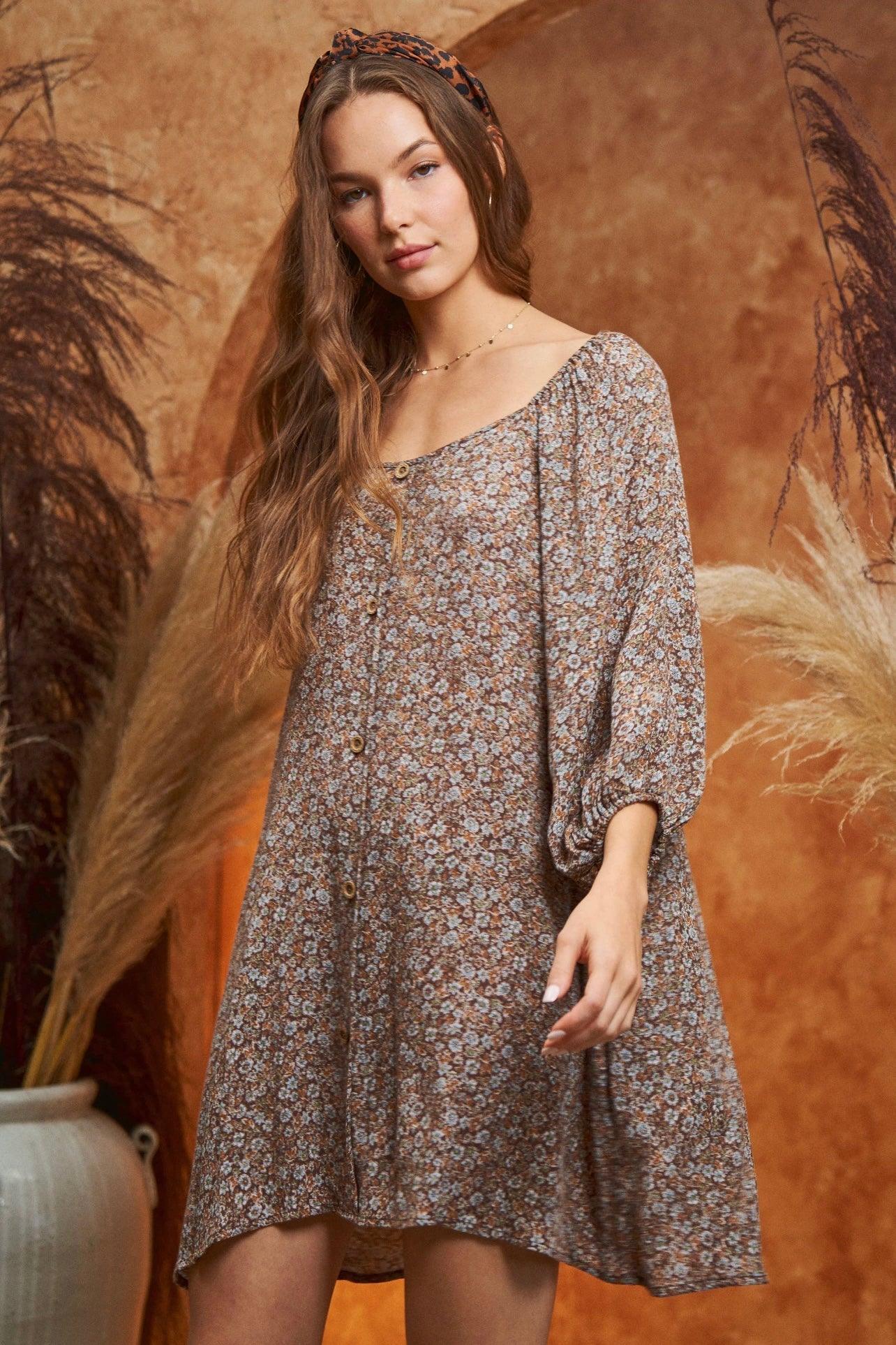Woman in floral Autumn Feels Dress with buttons and 3/4 sleeves standing against warm textured backdrop