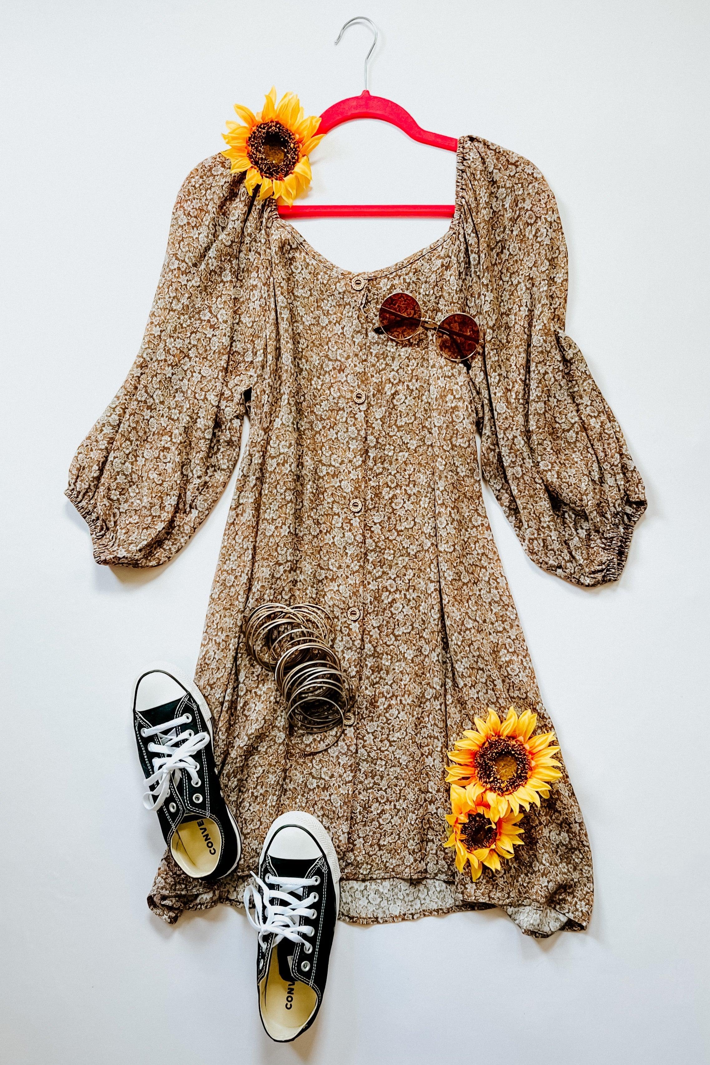 Brown floral Autumn Feels Dress with puff sleeves and buttons, styled with black sneakers, sunglasses, bangles, and sunflowers on red hanger