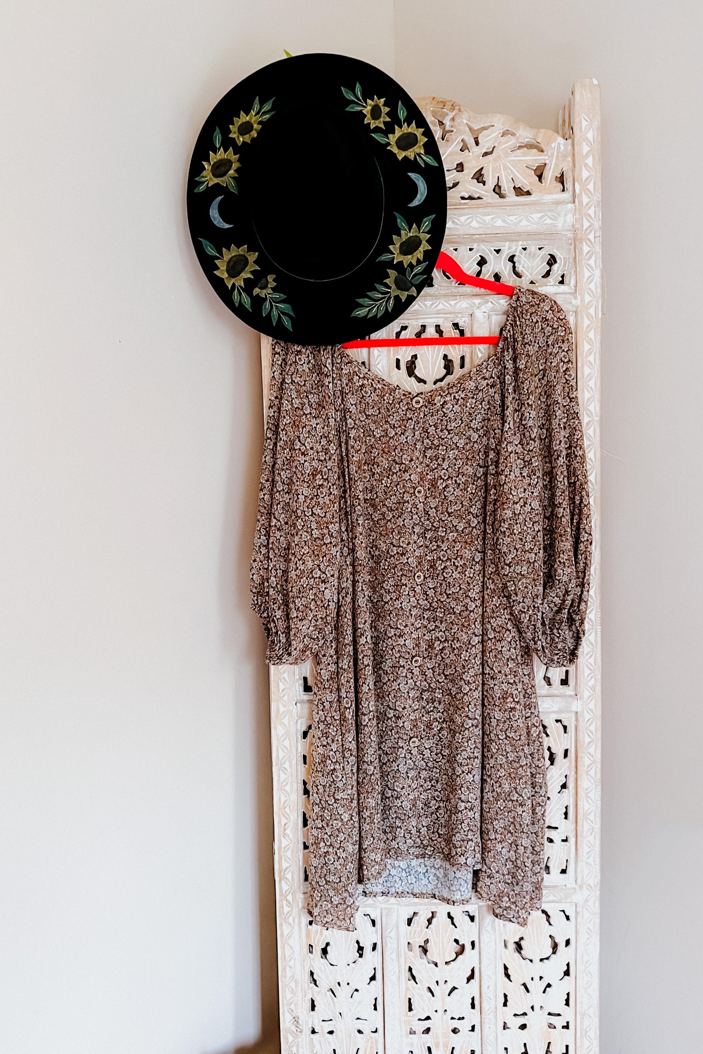 Autumn Feels Floral Dress with long puff sleeves on red hanger beside black sunflower and moon patterned hat