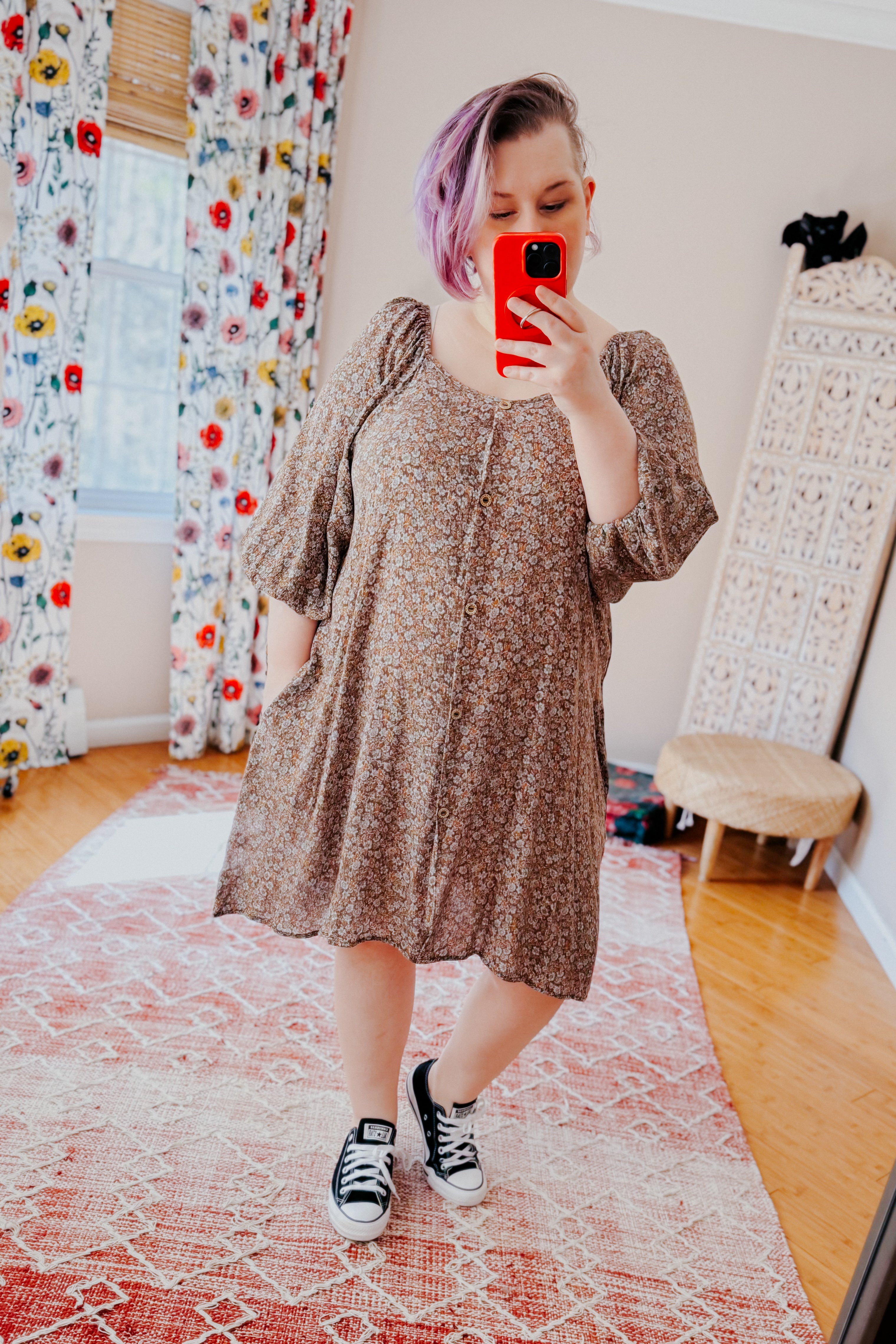 Person with lavender hair taking mirror selfie wearing loose Autumn Feels Floral Dress with puff sleeves and black sneakers in bright room