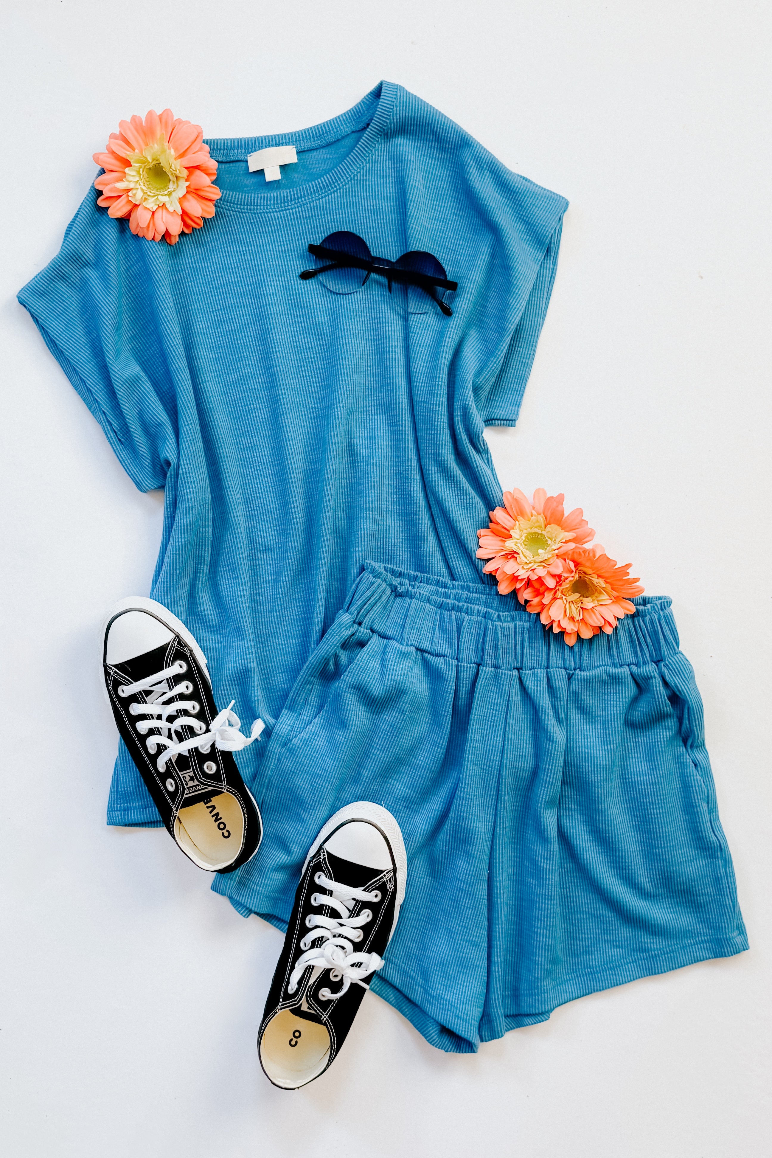 Blue outfit with shorts, t-shirt, and black sneakers on a white background