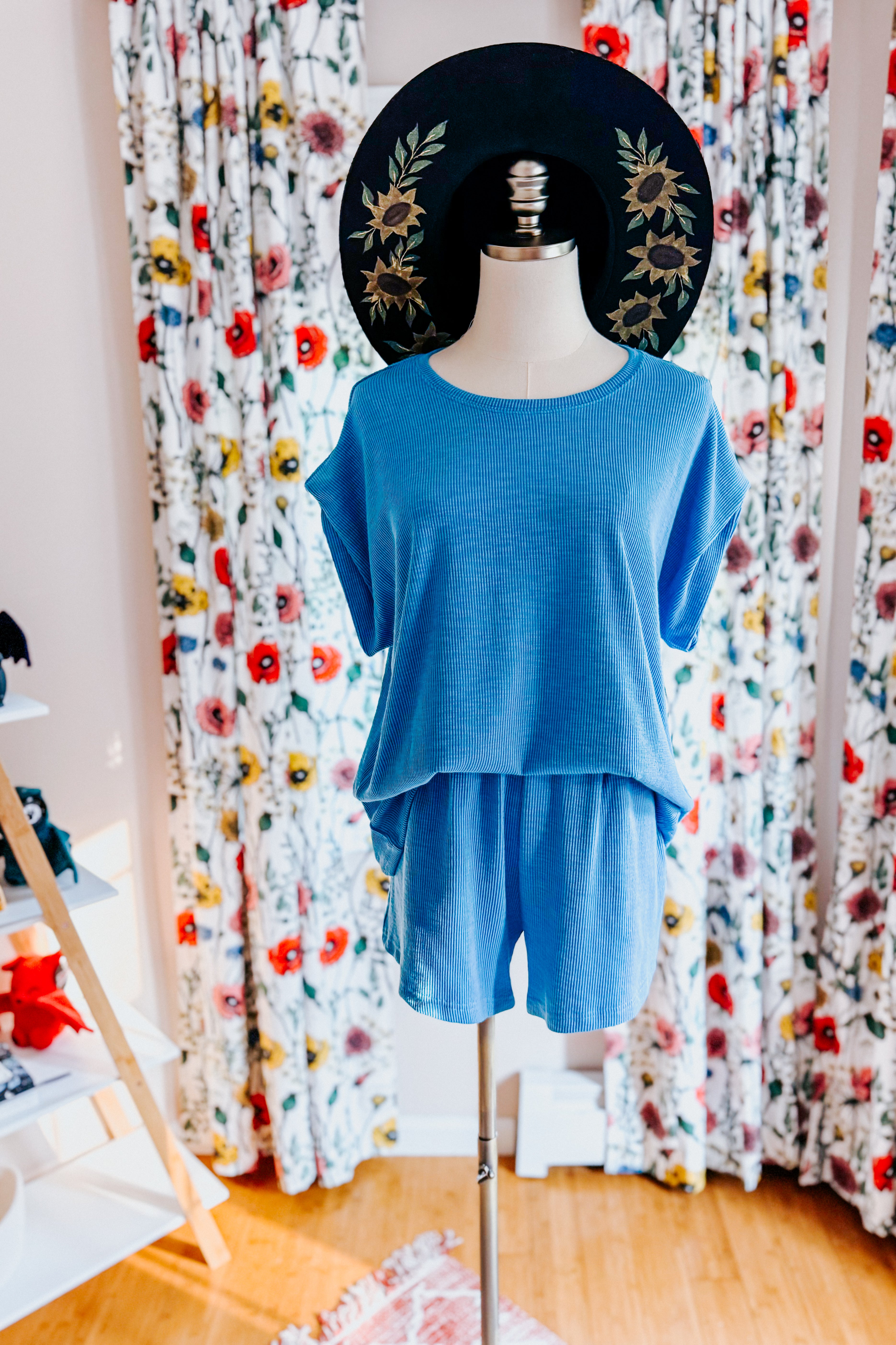 A dress form wearing a blue shorts and tee shirt set in an indoor setting.