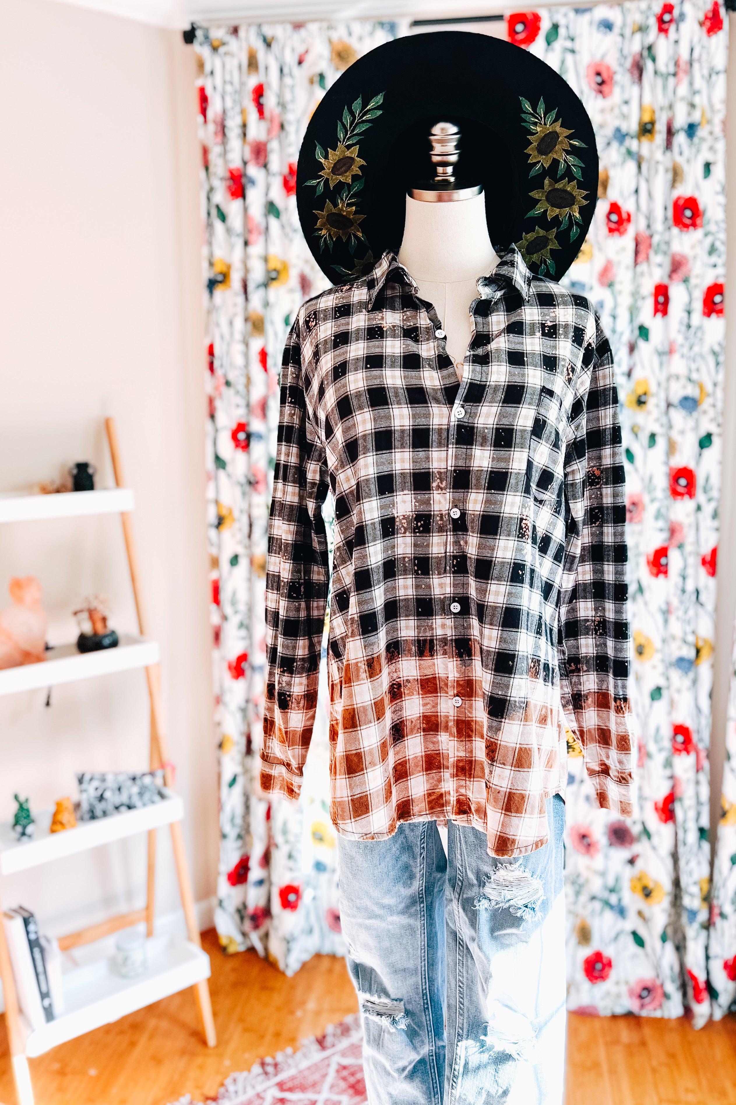 Mannequin wearing black and white bleached plaid flannel shirt paired with distressed light blue jeans and floral embroidered hat