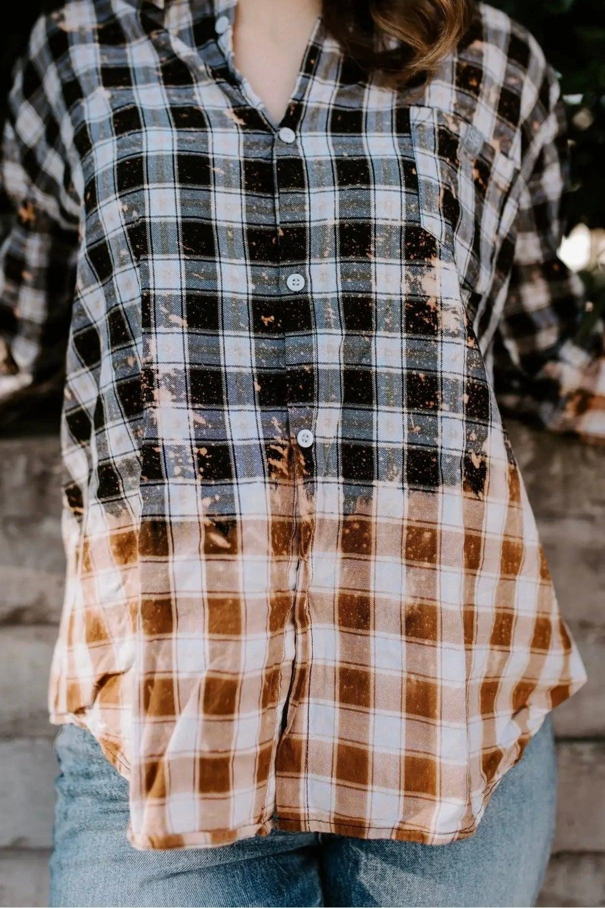 Close-up of unique bleached black and brown plaid flannel shirt worn with light blue jeans outdoors