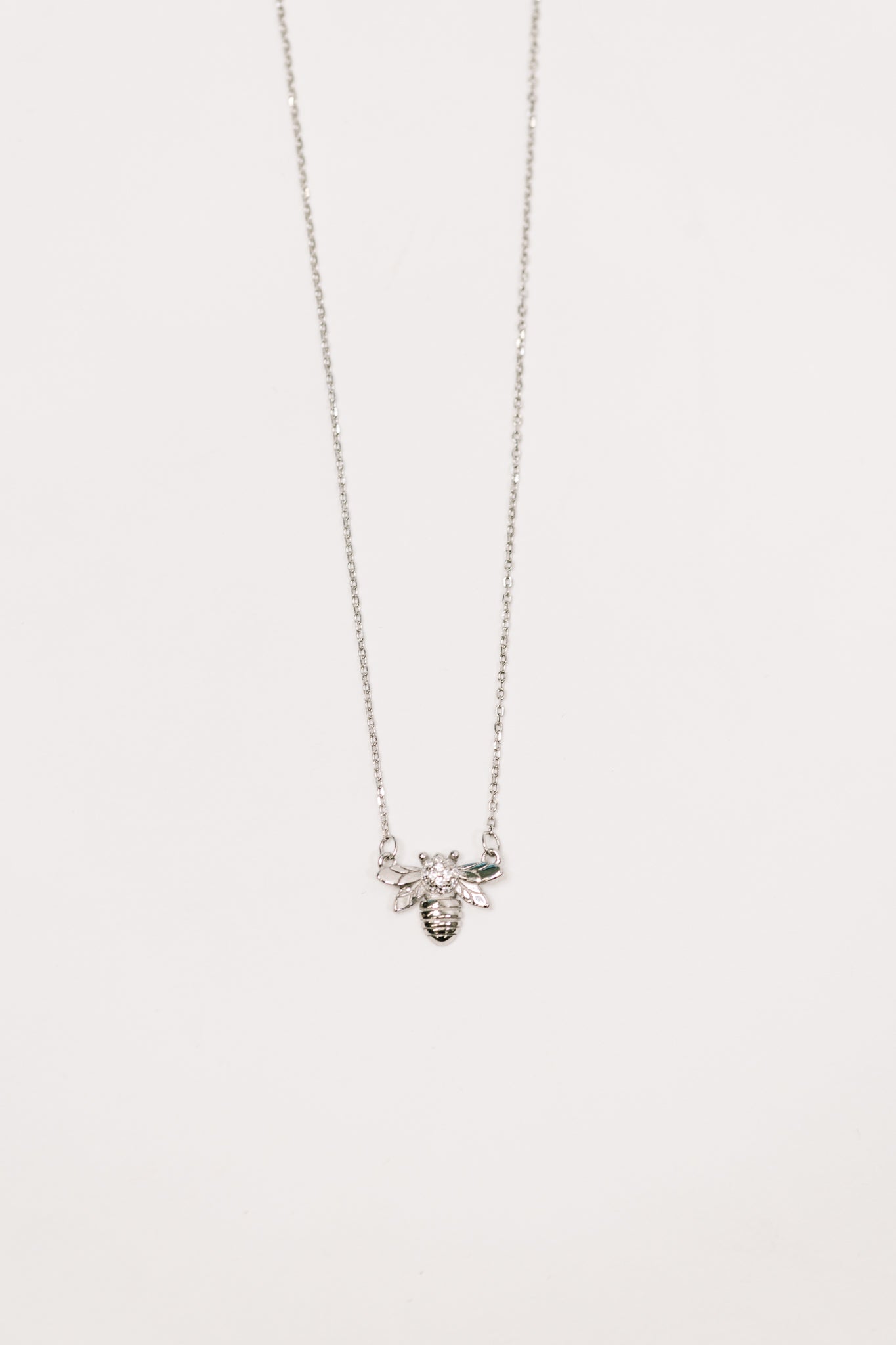Delicate silver necklace featuring a detailed bee pendant with sparkling zirconia stones on a fine chain