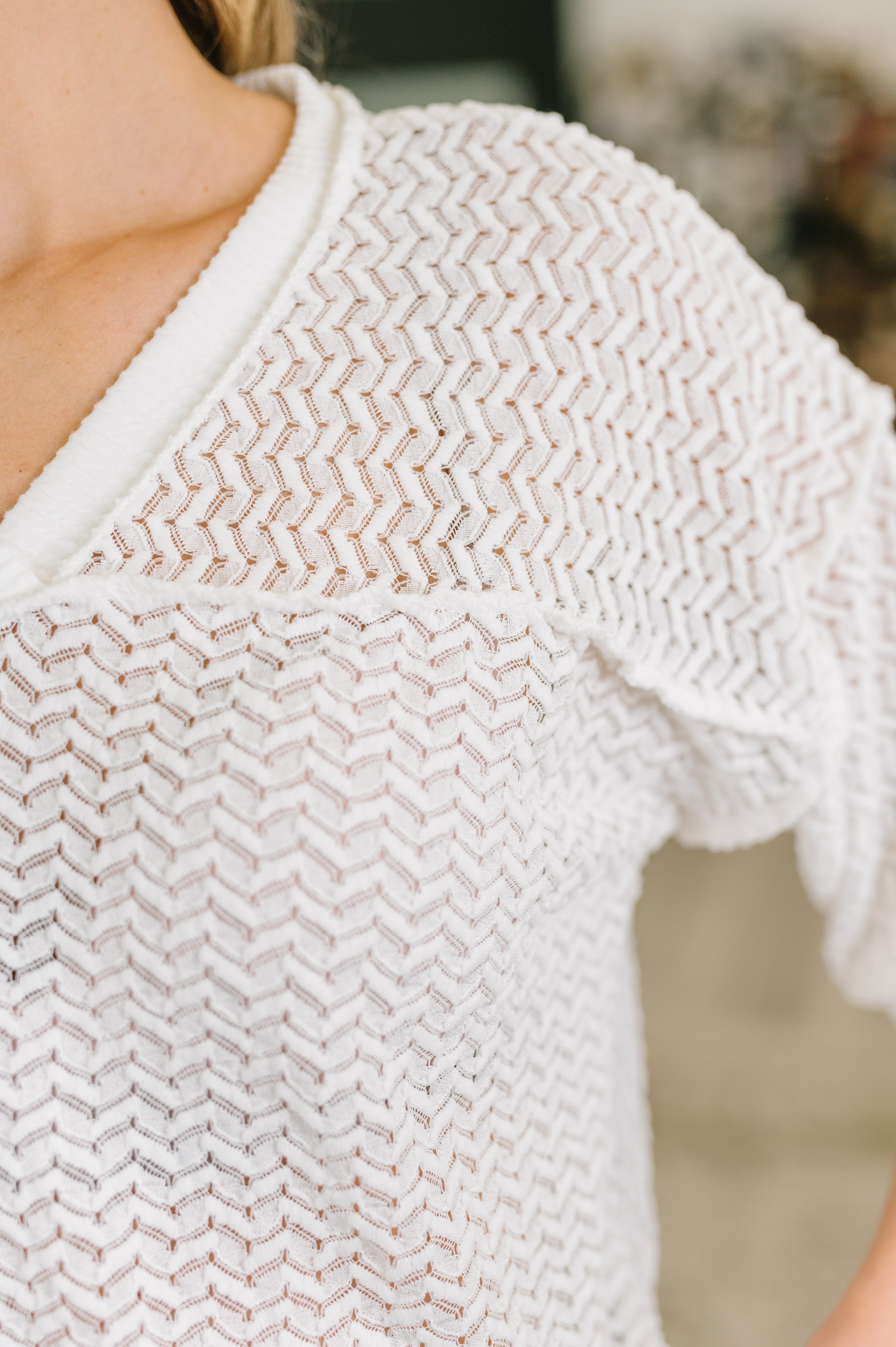Close-up of cream textured oversized top with sheer knit and cable ribbed details on neckline and shoulder