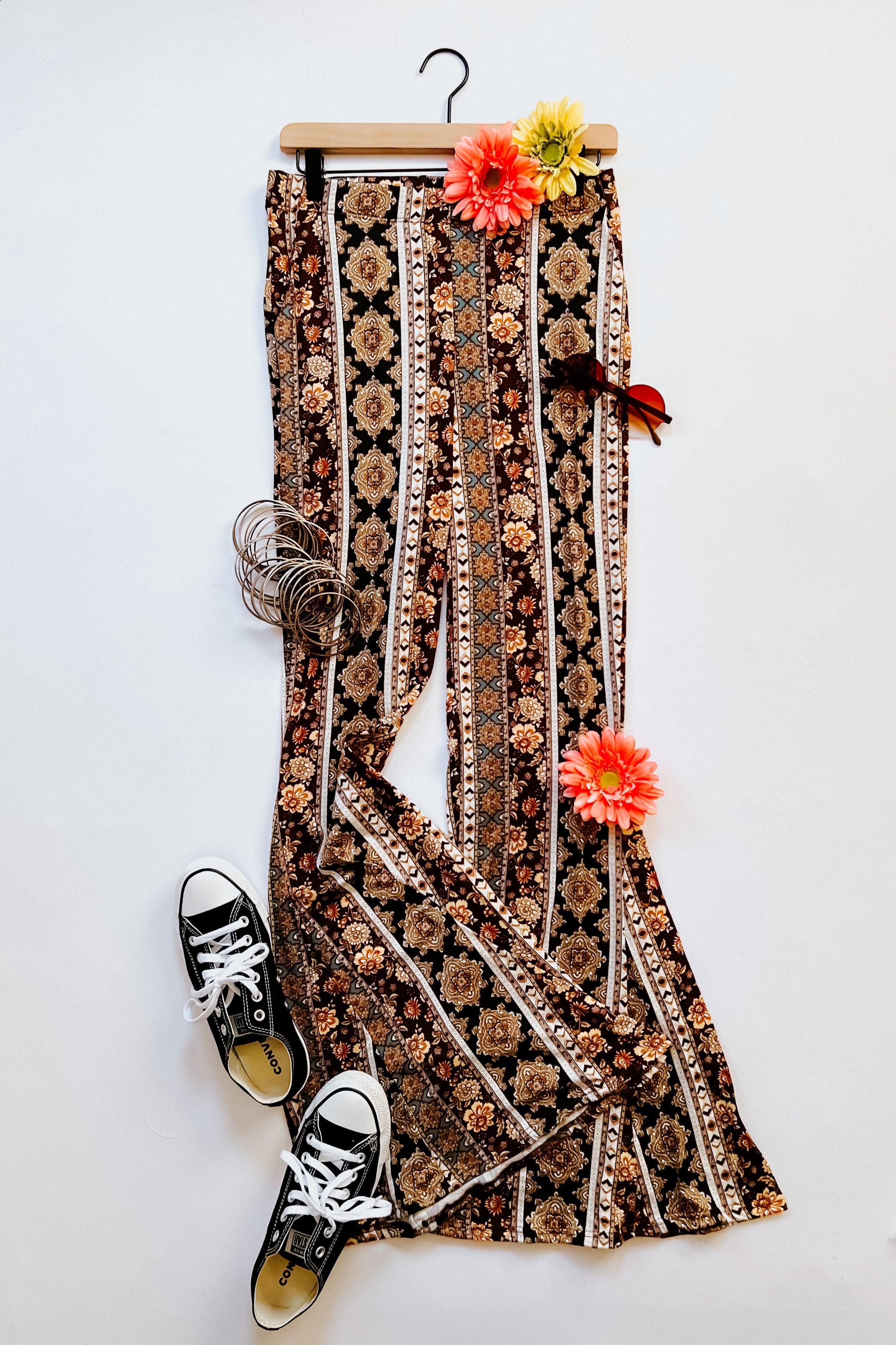 Bohemian patterned flared pants displayed with black sneakers, sunglasses, silver bangles, and vibrant artificial flowers