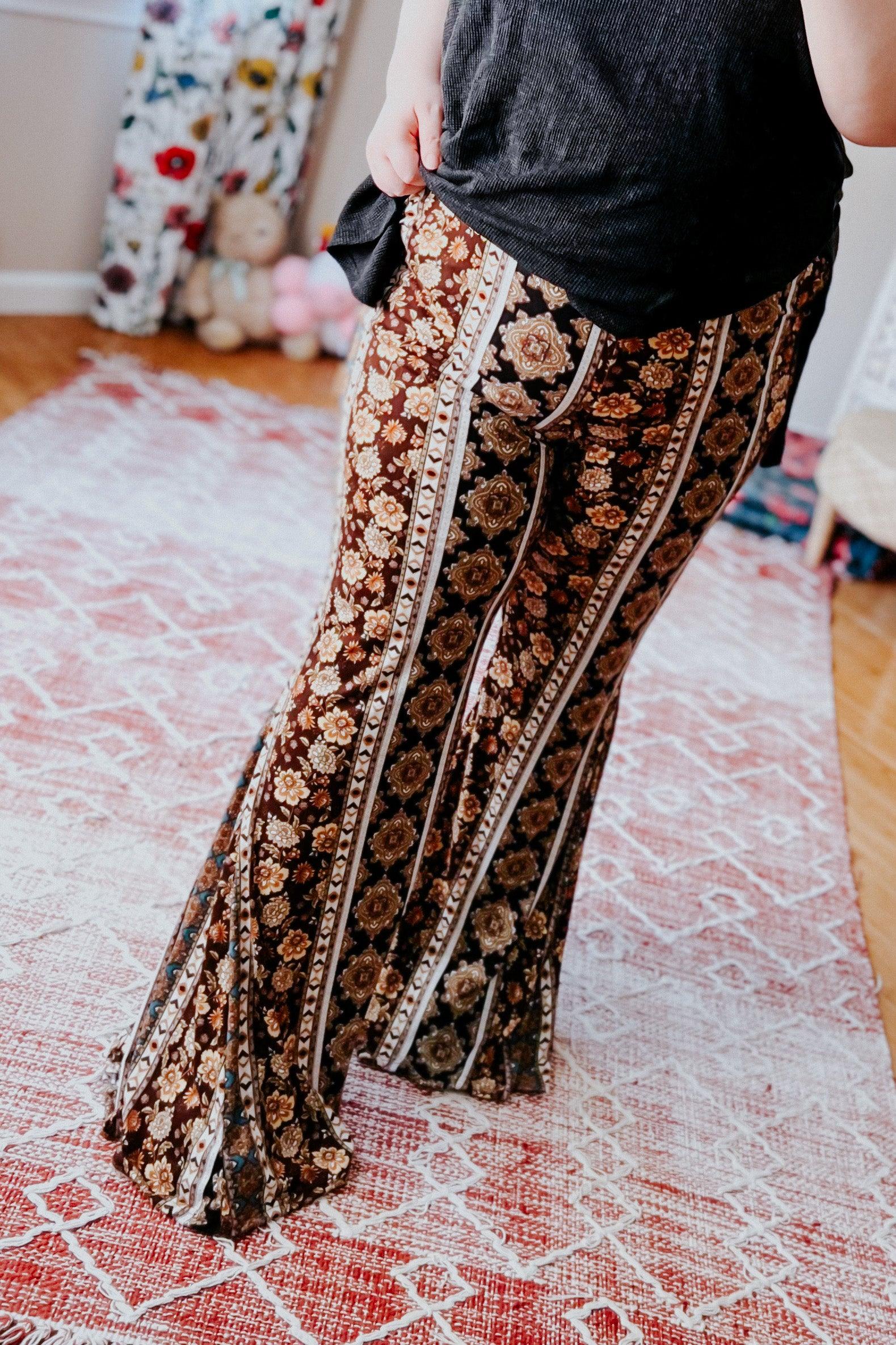 Woman wearing brown floral and striped patterned flared pants standing on red and white patterned rug indoors