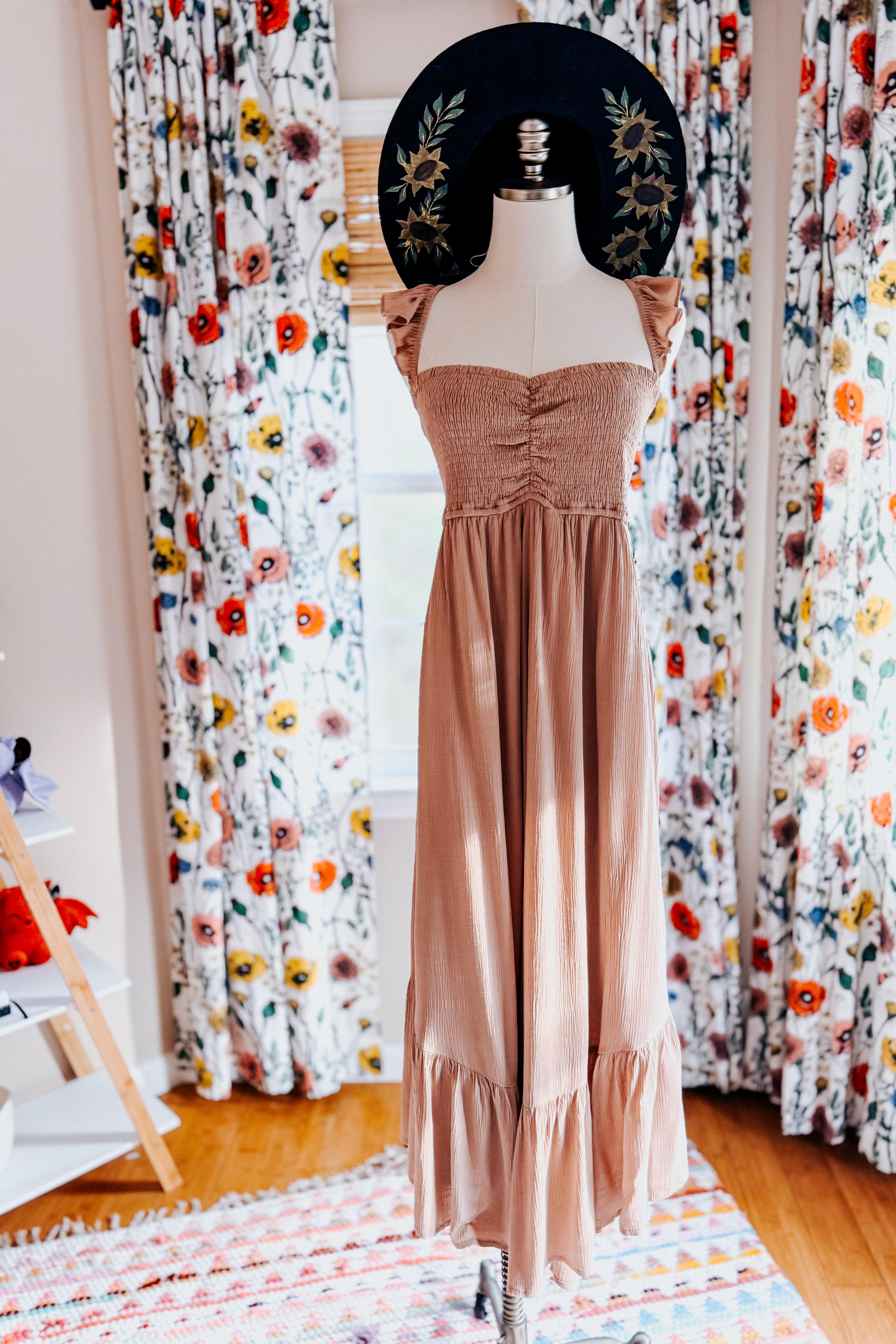 Sleeveless blush pink smocked bodice wide leg jumpsuit with ruffle straps displayed on mannequin indoors