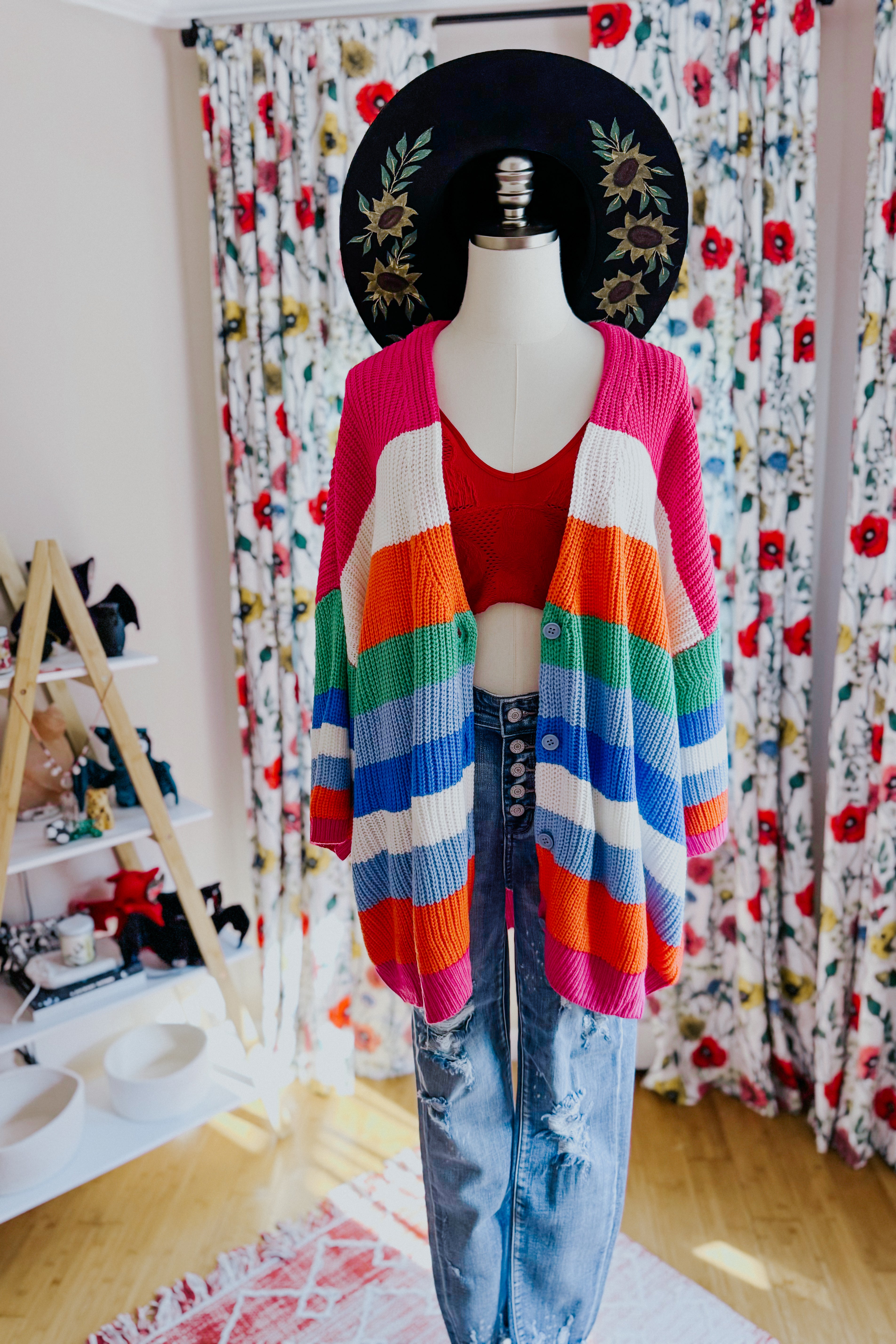 Colorful bold striped button-down cardigan with oversized fit styled on mannequin with red crop top and distressed jeans