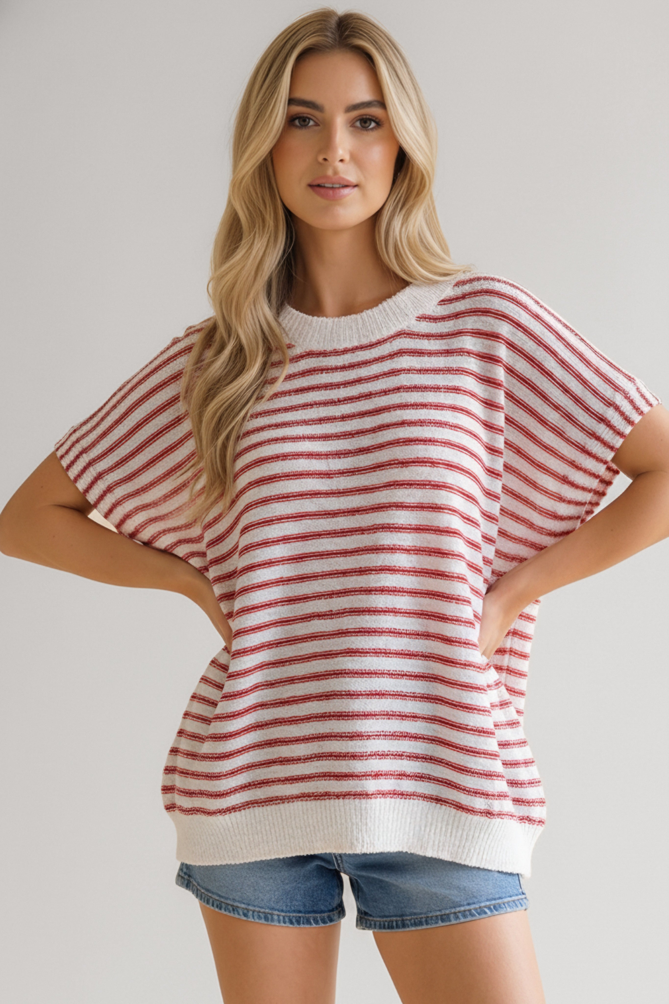 Woman wearing a relaxed fit red striped knit top with short sleeves paired with denim shorts in casual pose