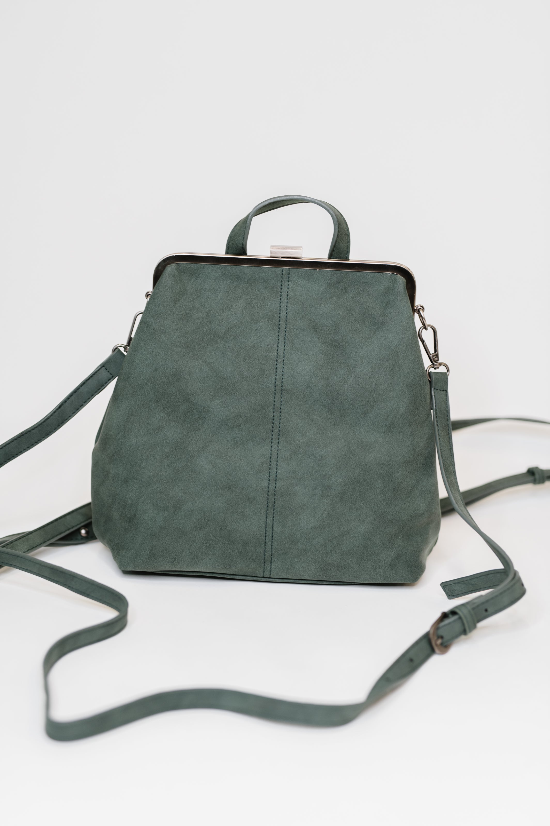 Green dainty backpack with silver frame clasp and adjustable straps standing against plain white background