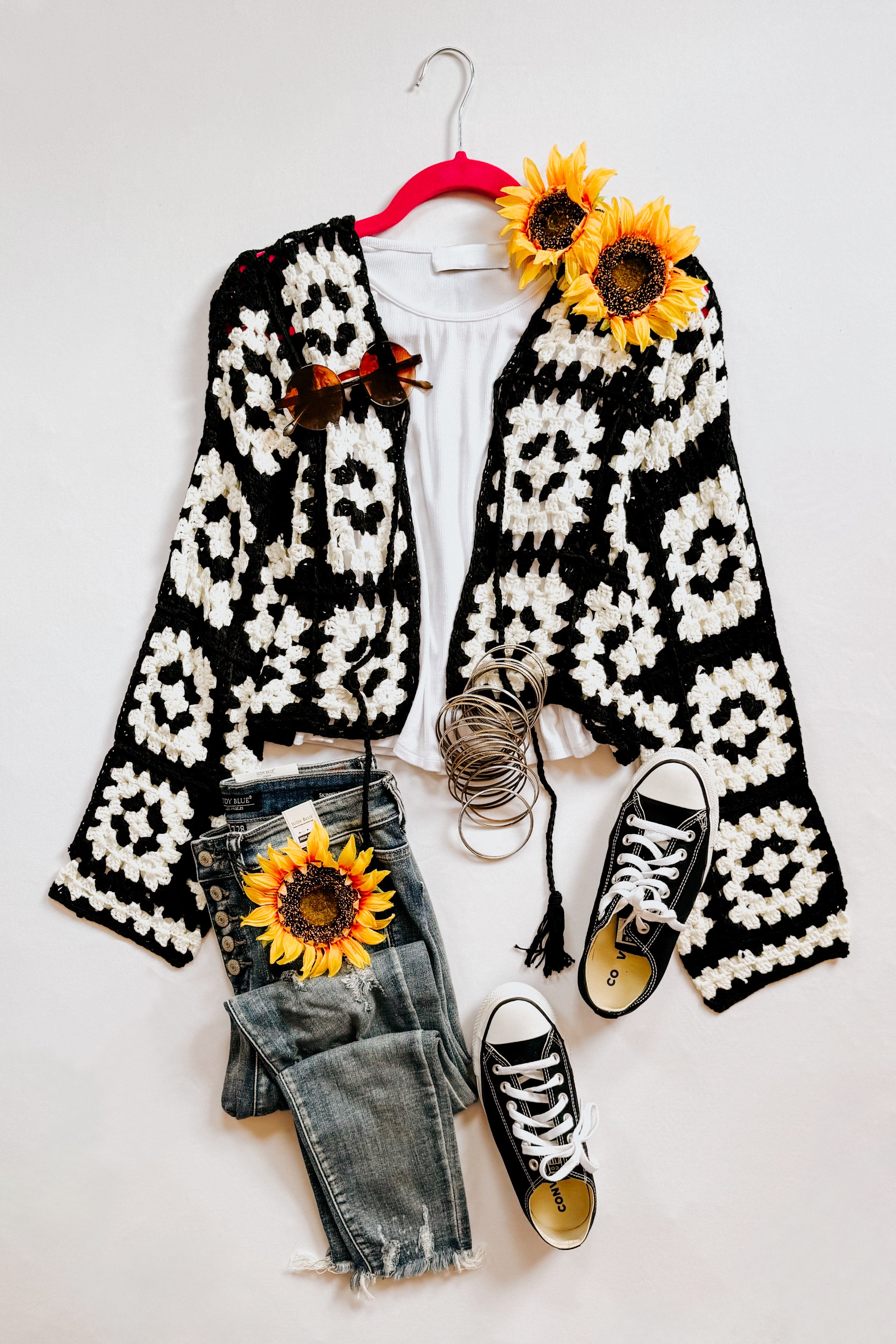 Black and white crochet cropped cardigan styled with white tee, distressed jeans, black sneakers, and sunflower accessories
