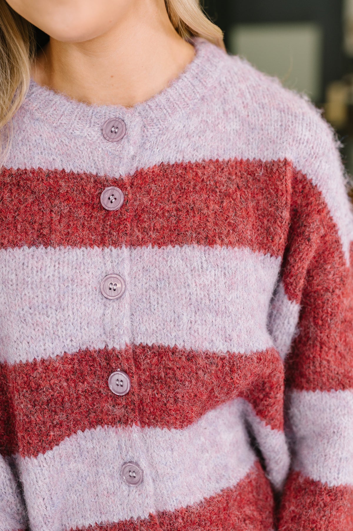 Close view of a woman wearing a red and purple striped brushed knit button front sweater with a ribbed round neckline