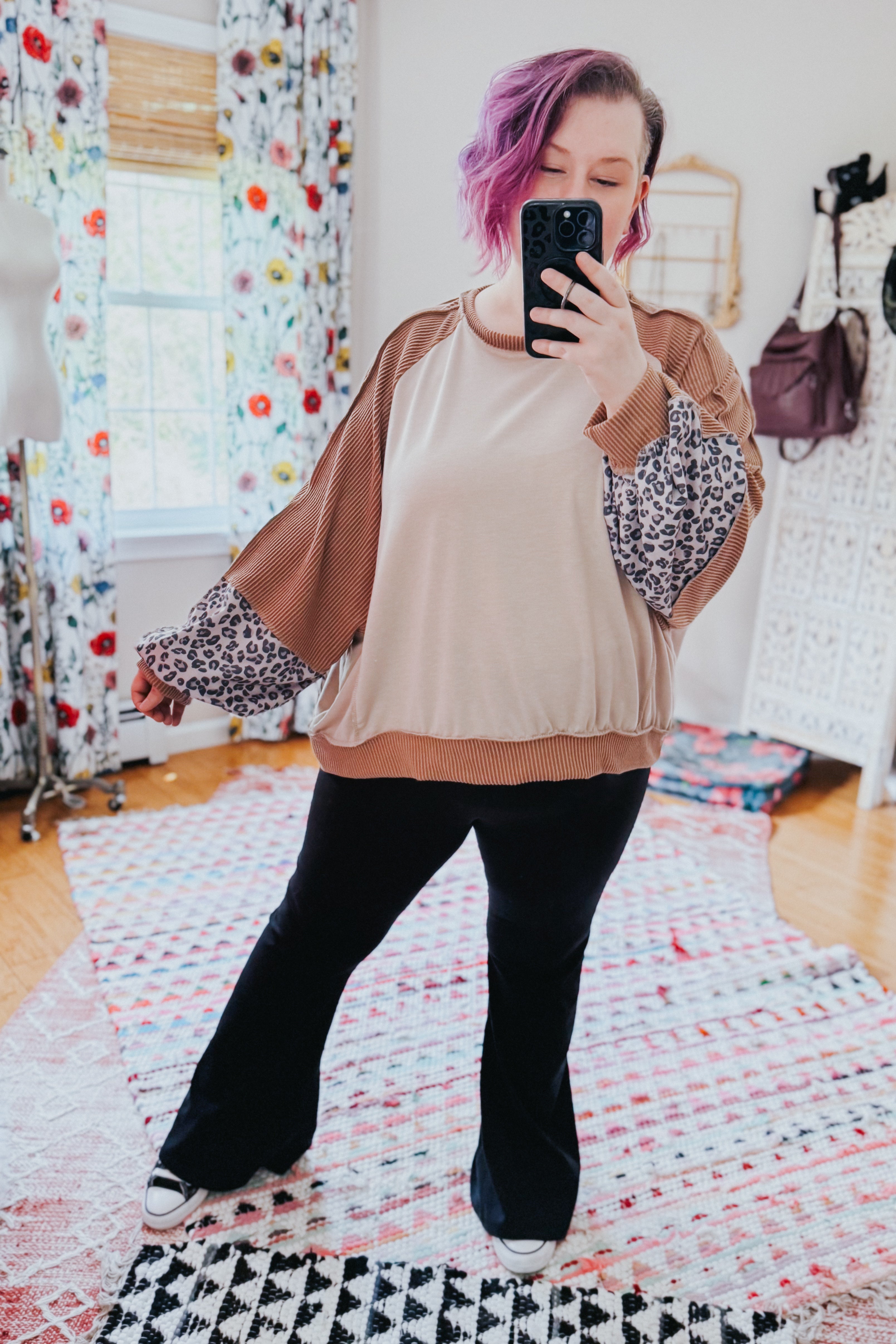 Woman taking mirror selfie wearing beige dolman colorblock terry top with brown ribbed and leopard print sleeves paired with black pants