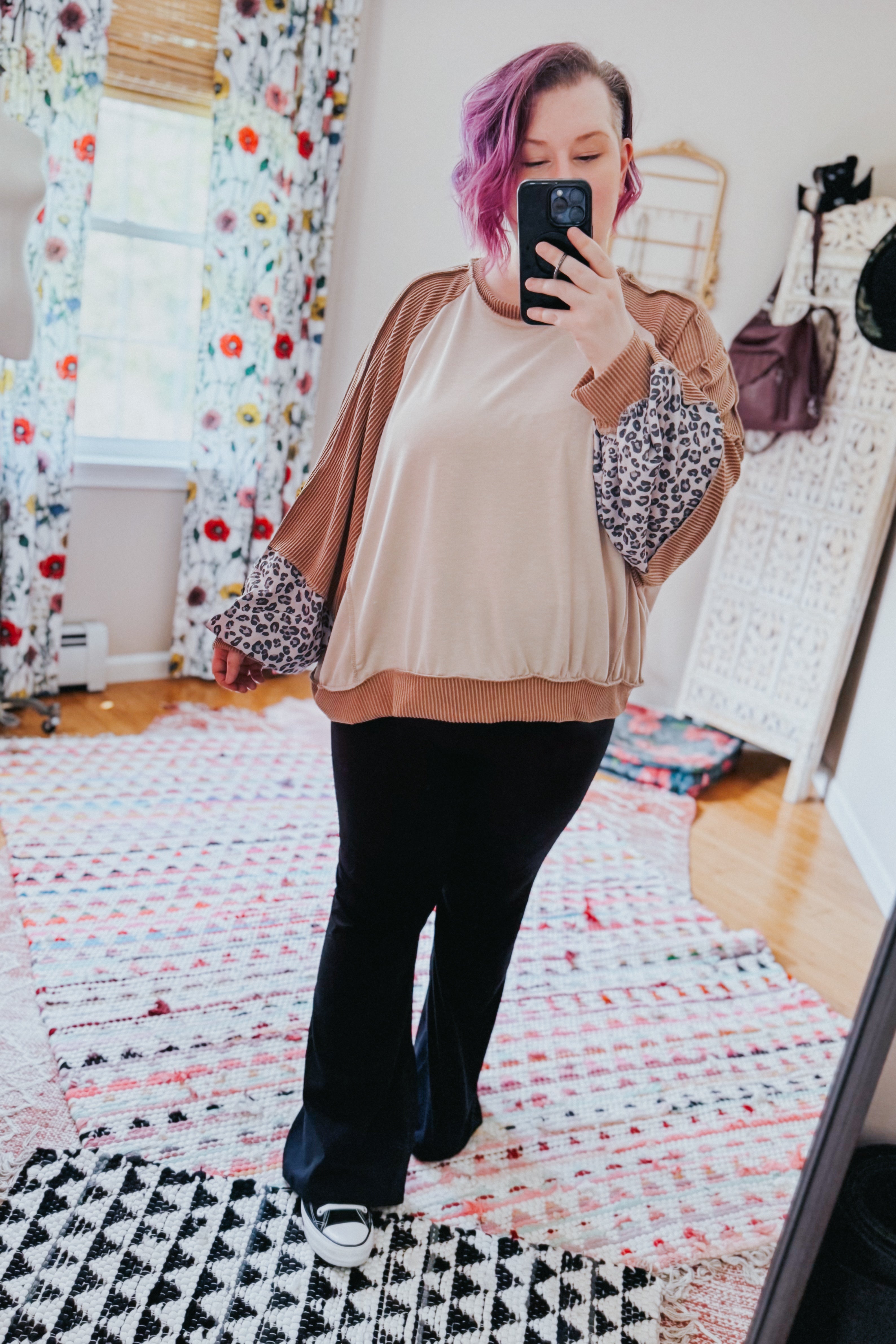 Woman taking mirror selfie wearing beige colorblock dolman top with leopard and brown ribbed sleeves paired with black pants