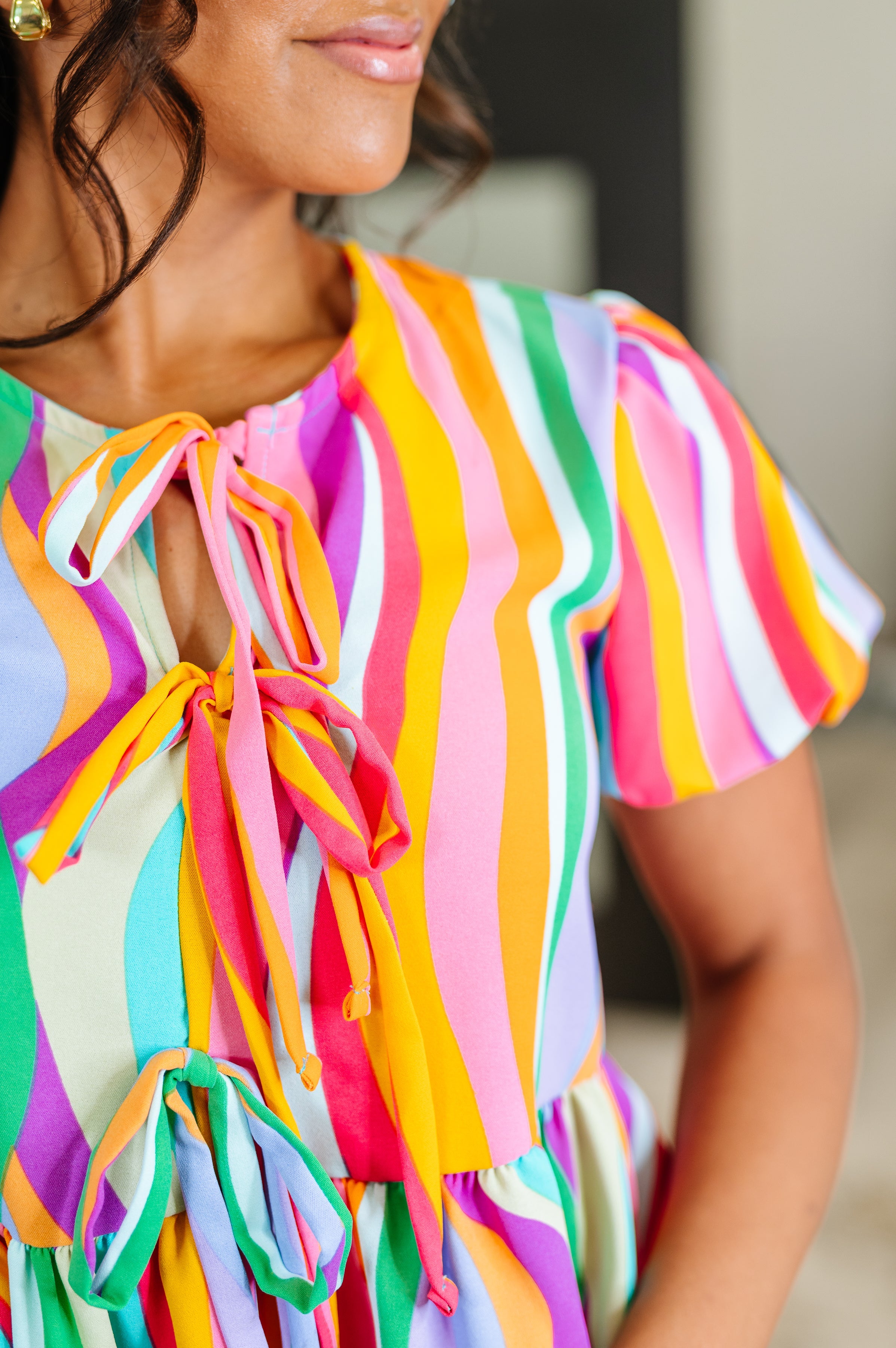 Close-up of a woman wearing a multicolored vertical striped blouse with puff sleeves and front tie details