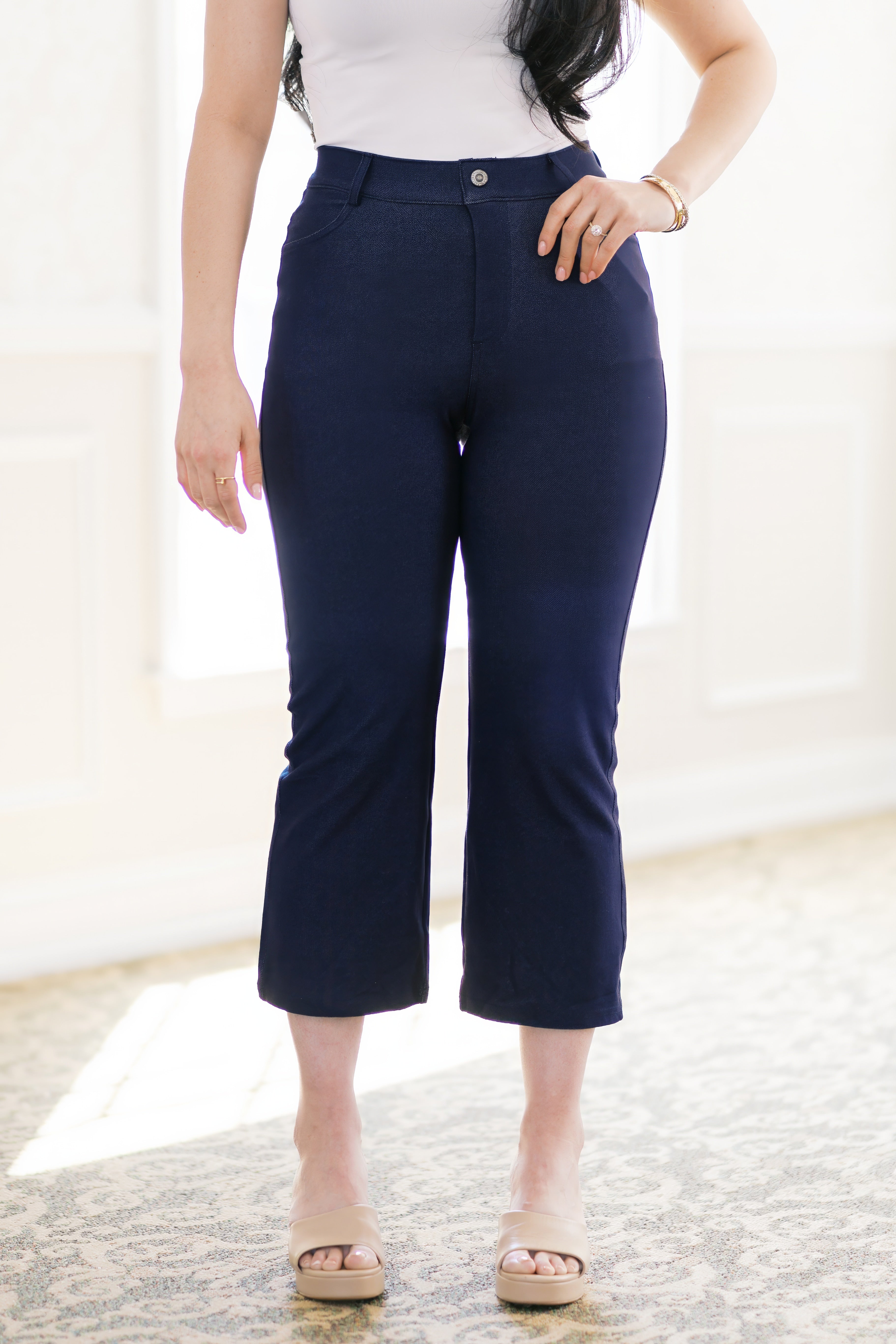 Front view of woman wearing navy cropped pants with button closure and beige open-toe sandals indoors