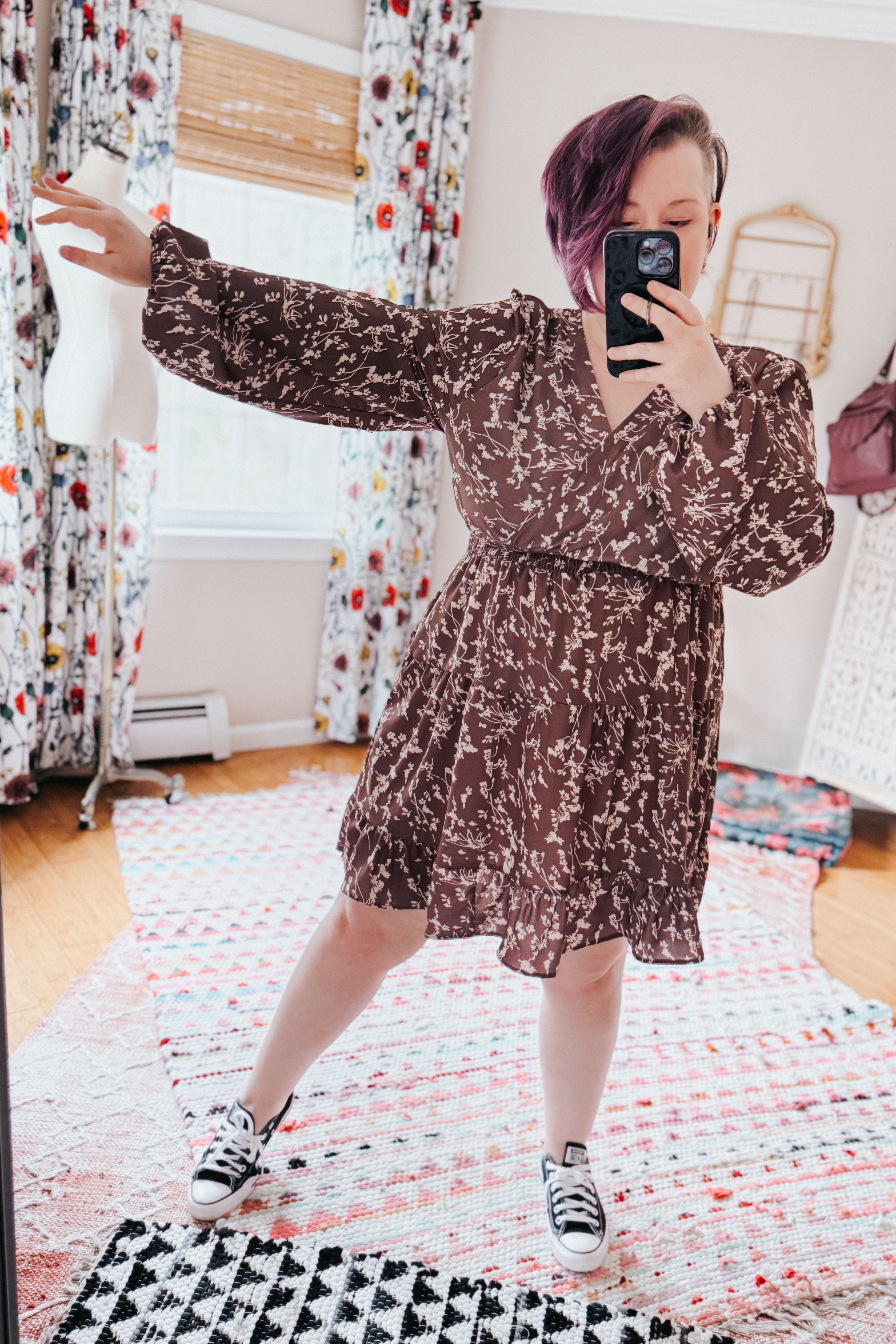 Woman wearing cocoa brown floral smocked waist dress with long sleeves and V-neck paired with black sneakers indoors