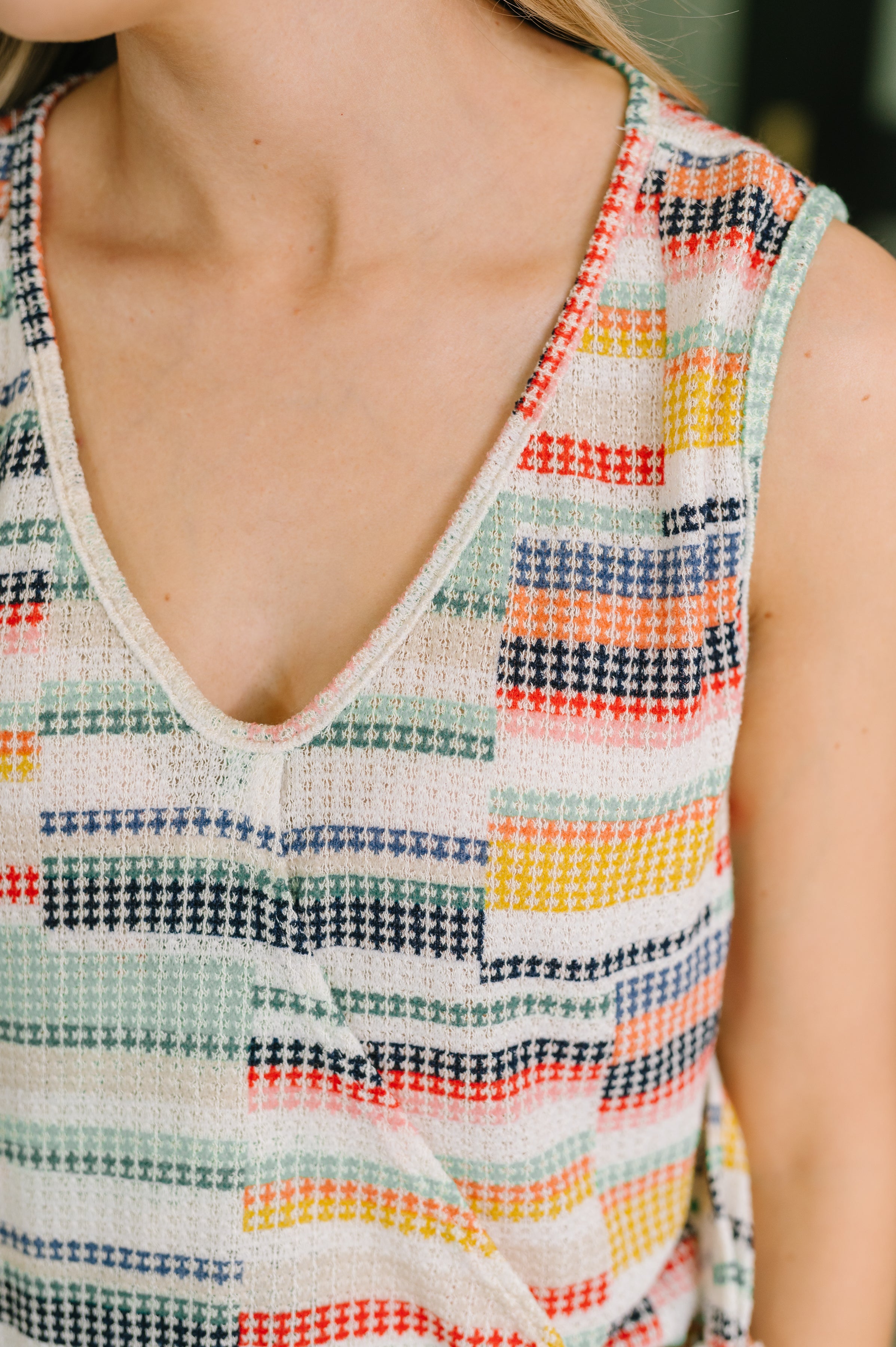 Close-up of a sleeveless knit tank top featuring a colorful abstract check pattern with a soft v-neckline
