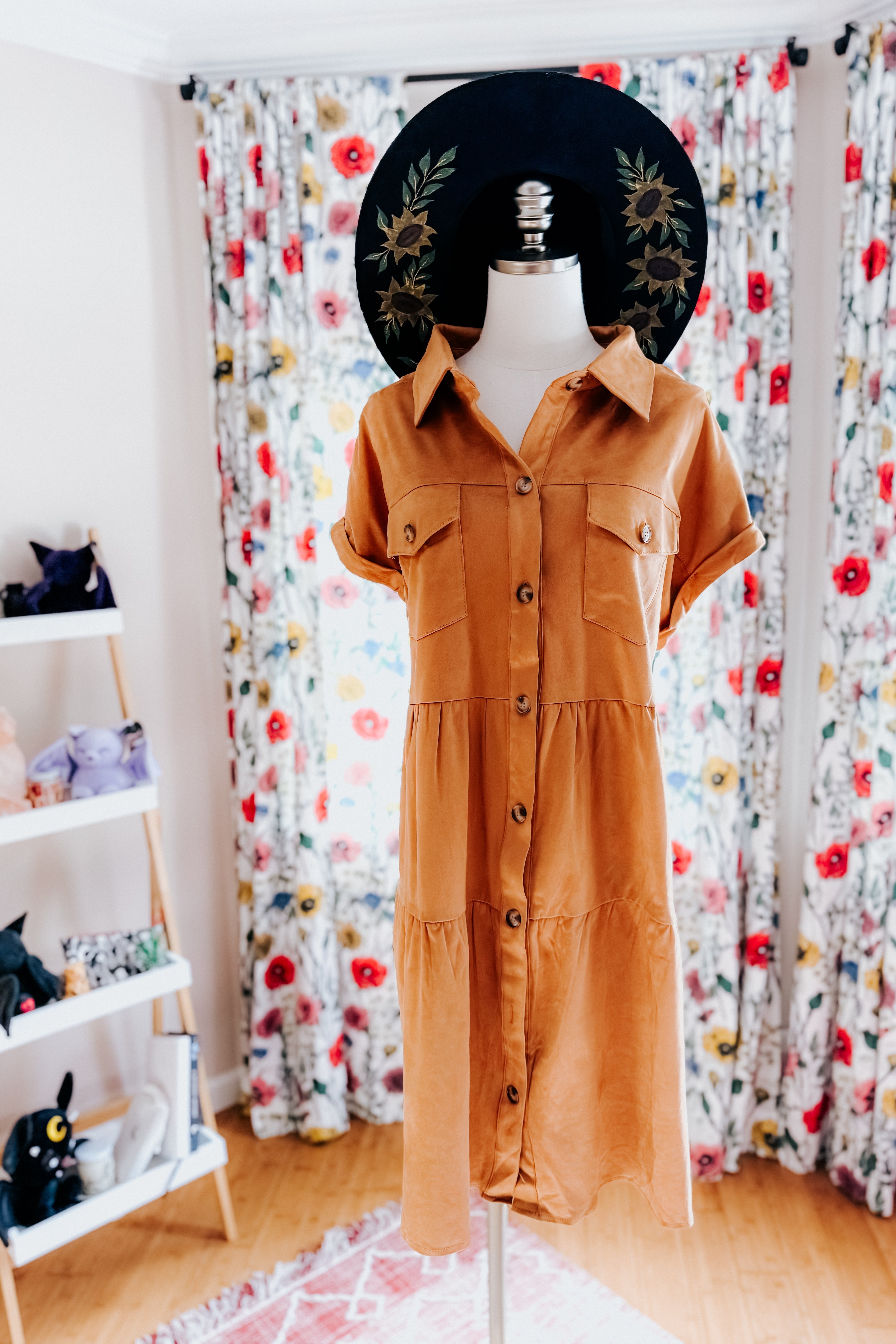 Button-front tan faux suede shirt dress with short sleeves and chest pockets displayed on a mannequin indoors