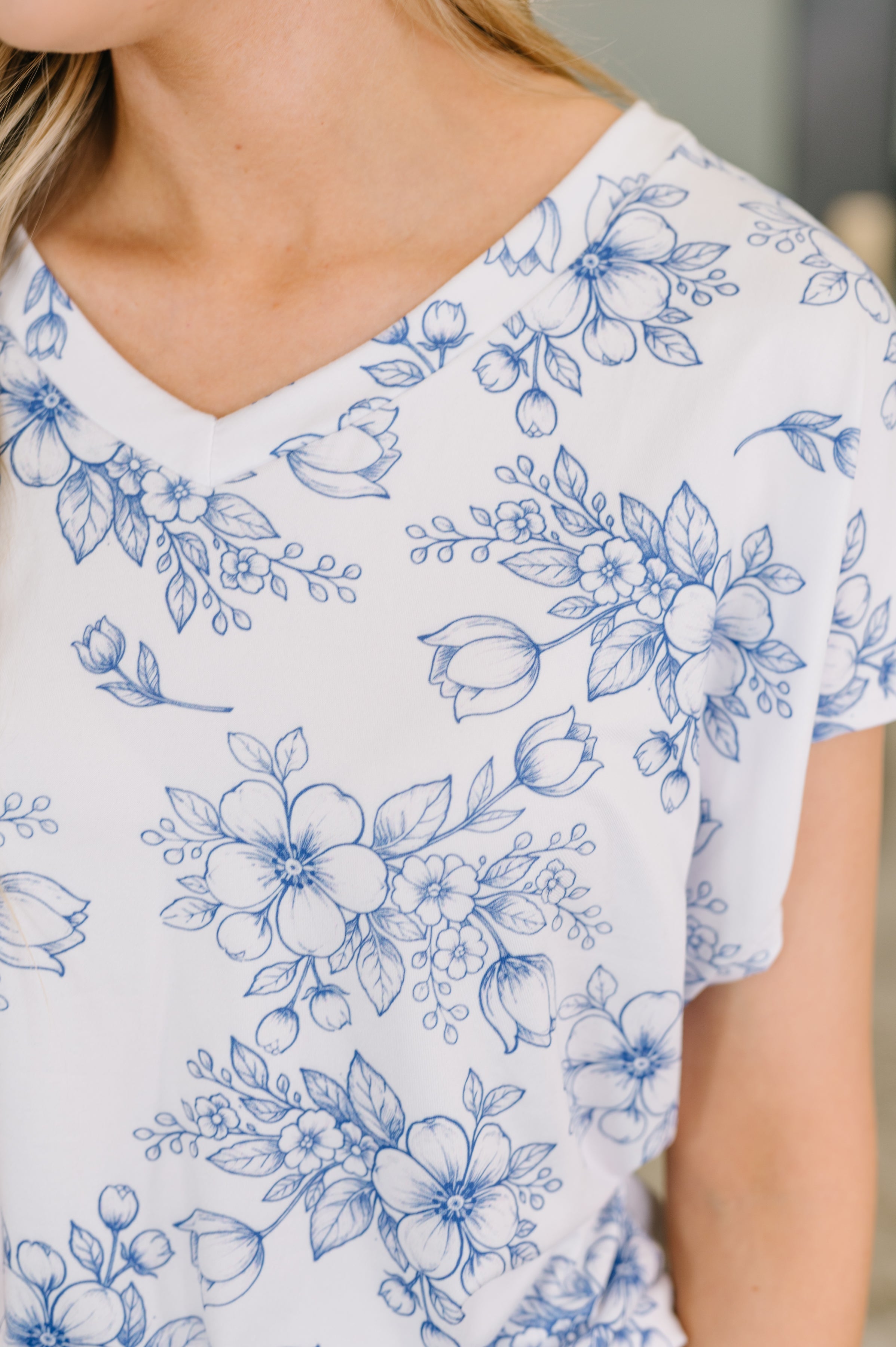 Close-up of cream V-neck top with delicate blue floral print, showcasing soft jersey knit and free-spirited style.