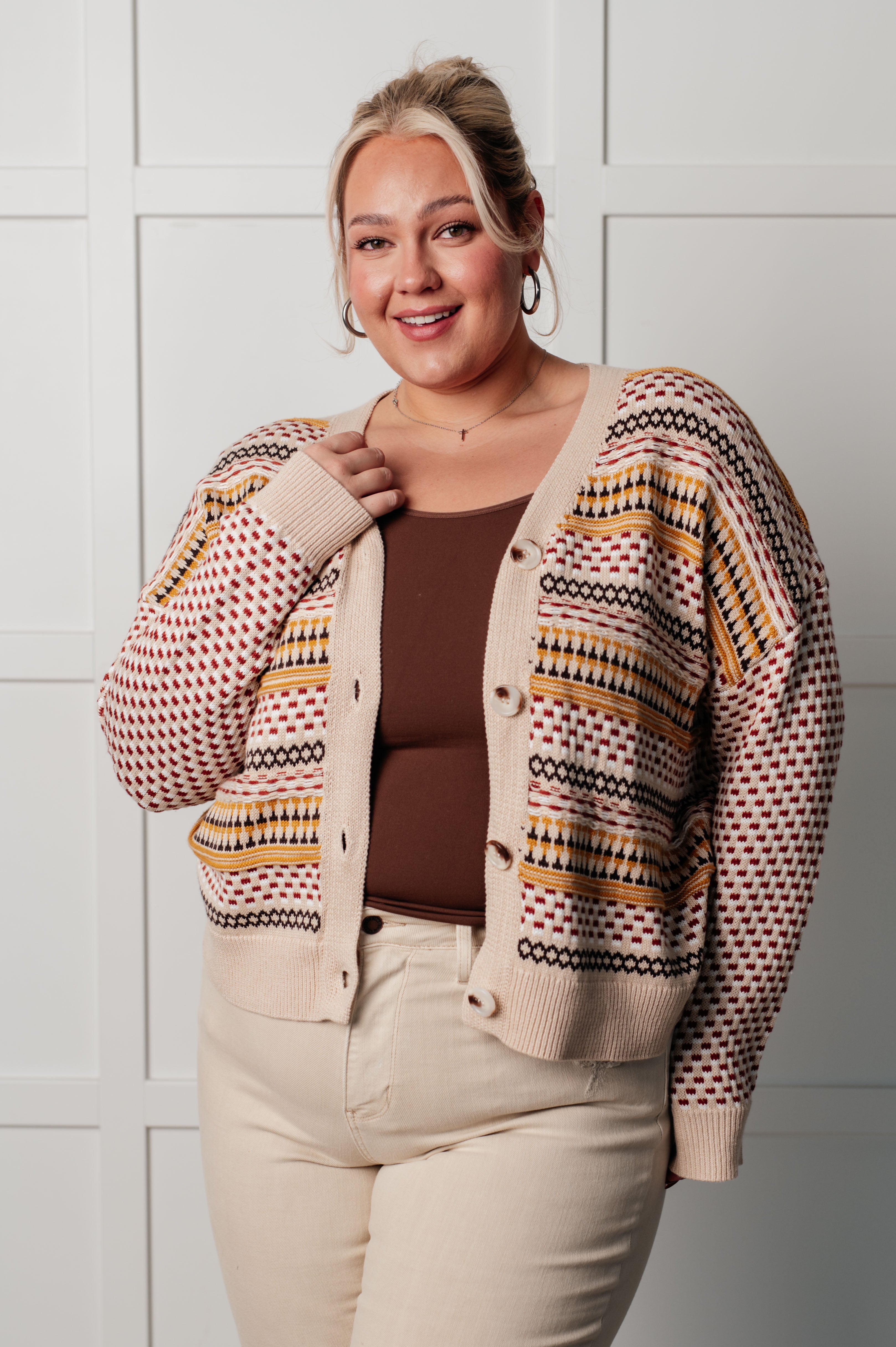 Curvy woman wearing buttoned Effortless Elements cardigan with red, mustard, and black stripes over brown top and cream pants indoors