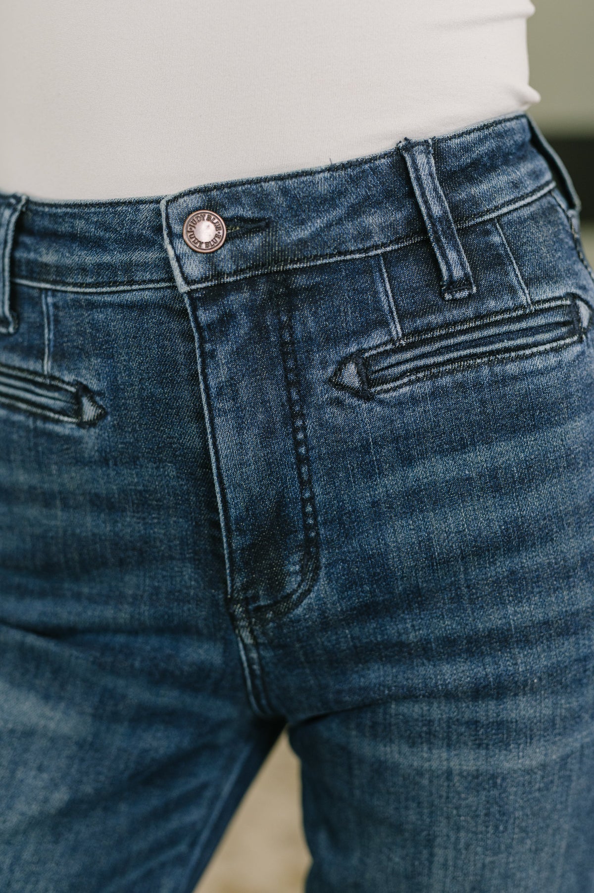 Close-up of blue high waist bootcut jeans featuring a button closure belt loops and welt pockets