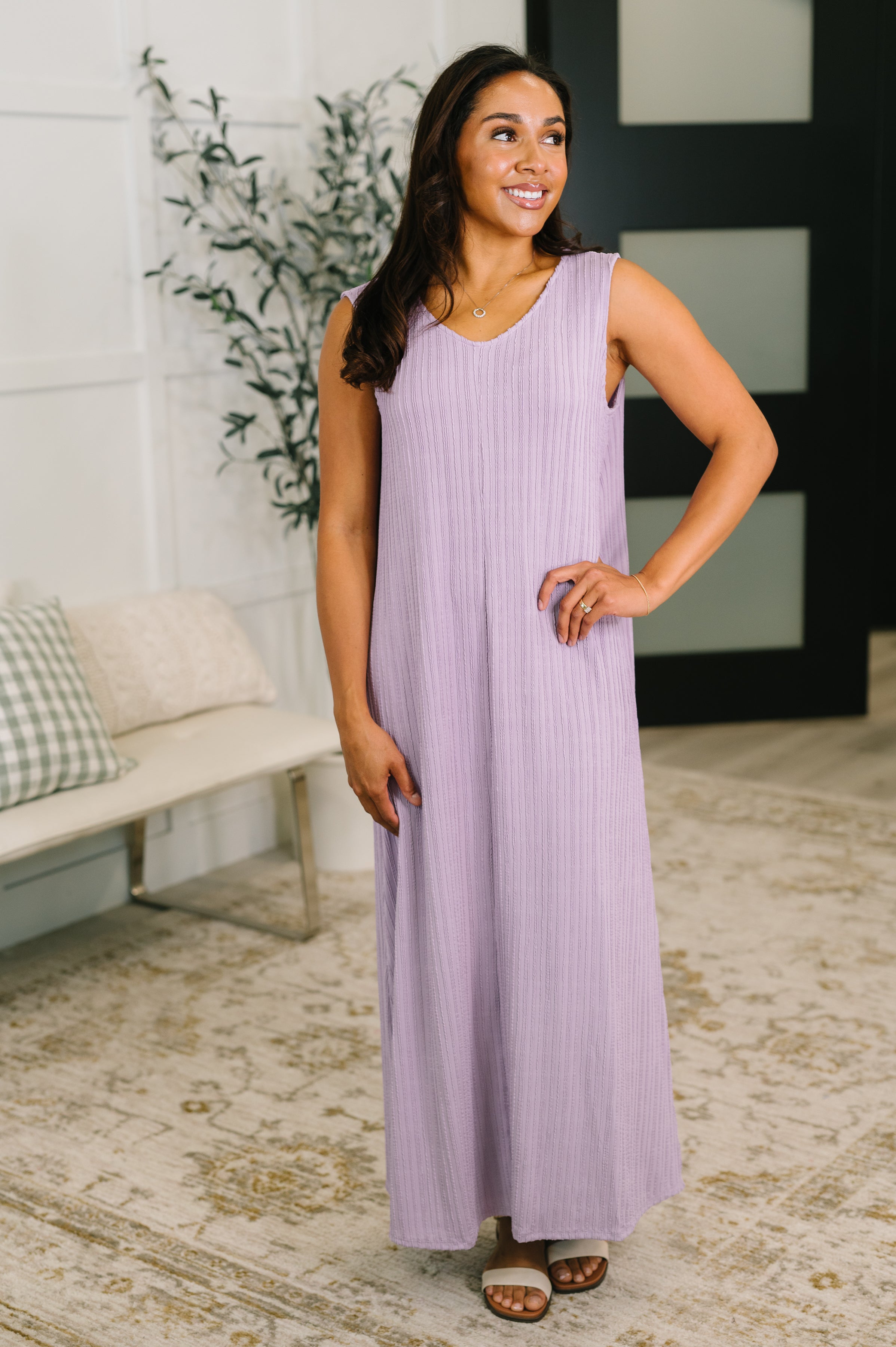 Woman wearing lavender sleeveless maxi dress with subtle vertical texture in cozy indoor setting smiling confidently