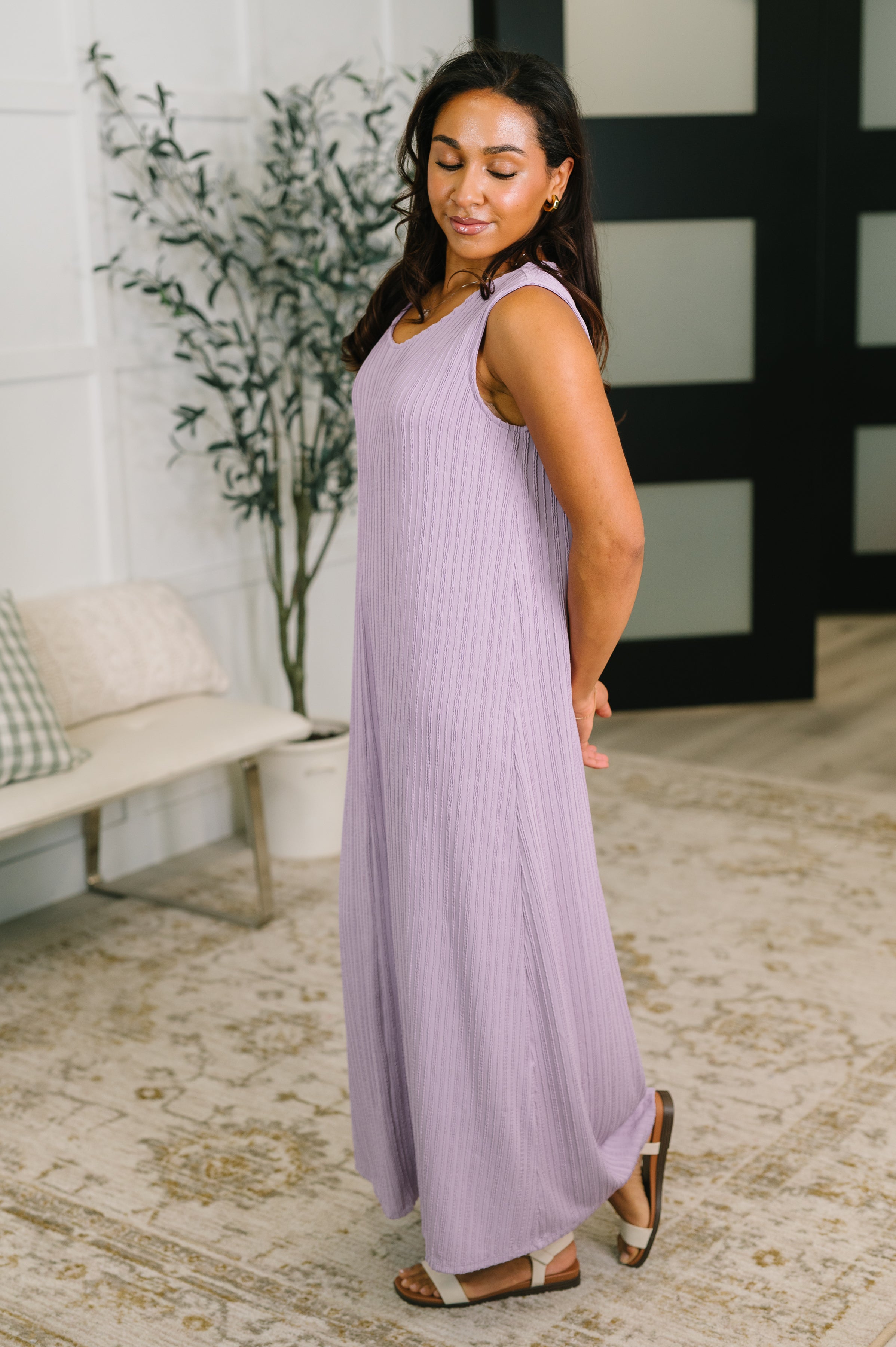 Woman wearing sleeveless lavender maxi dress with vertical ribbed texture and casual sandals indoors
