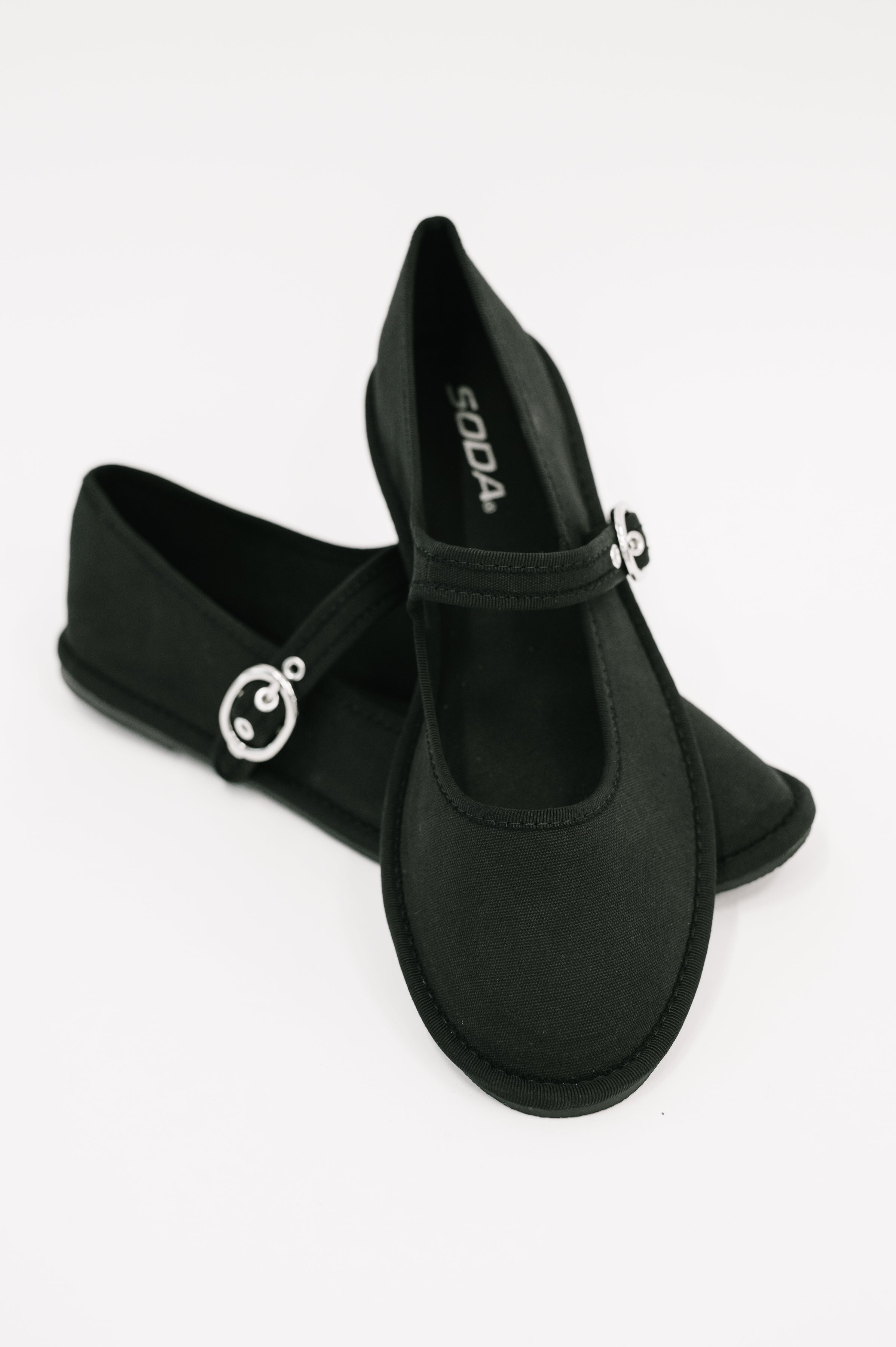 Pair of black flats with charming round buckle straps displayed on a clean white background